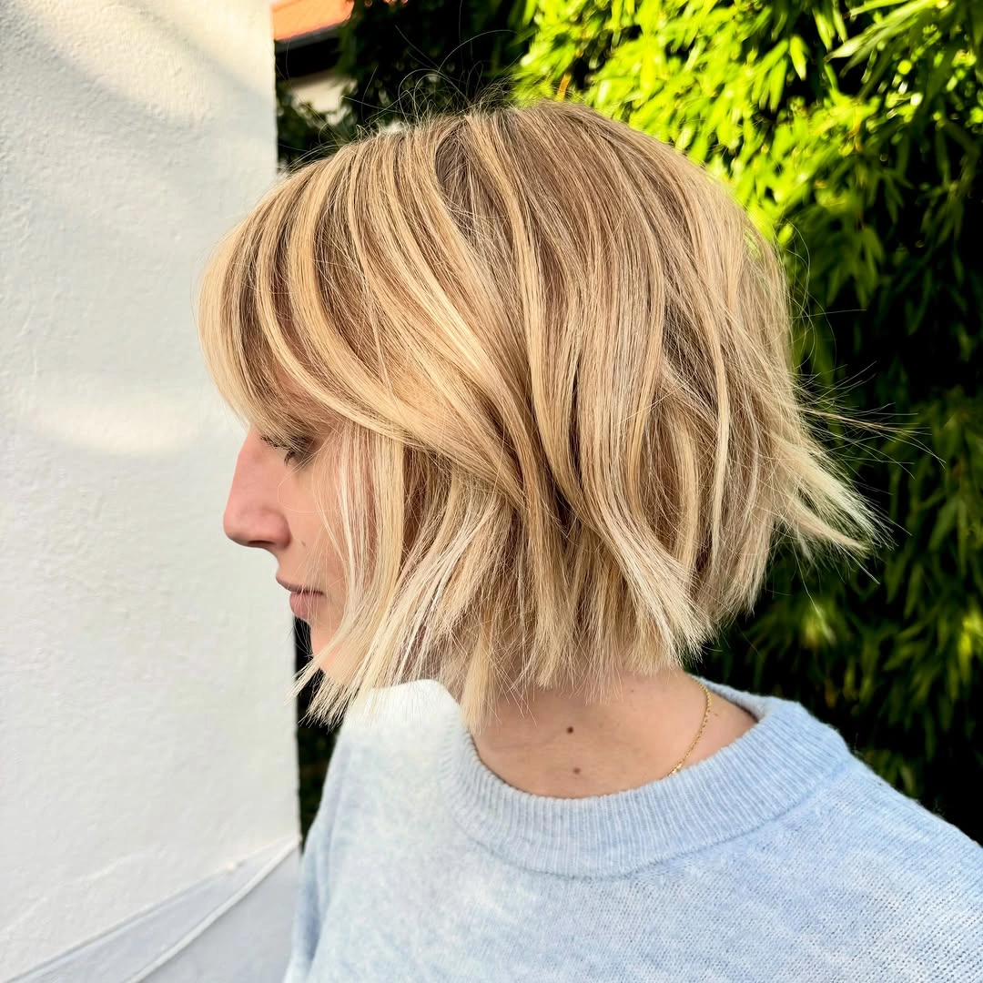 Short warm blonde bob with bangs and piecey ends
