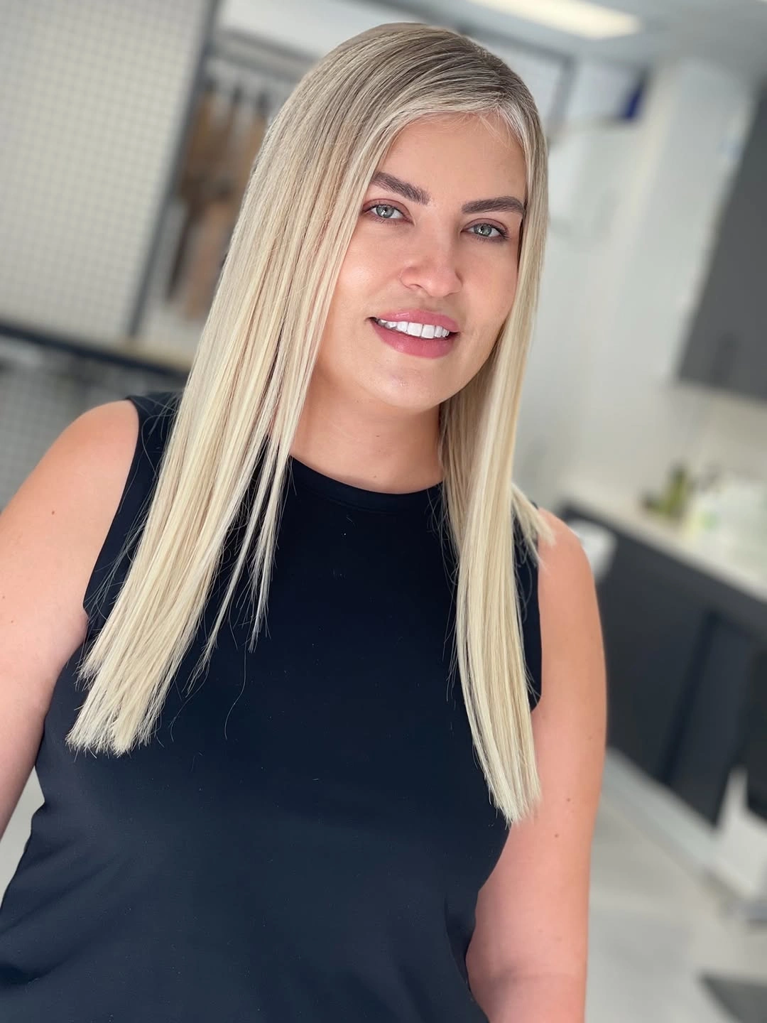 Sleek straight pale blonde hair with darker root and blunt ends