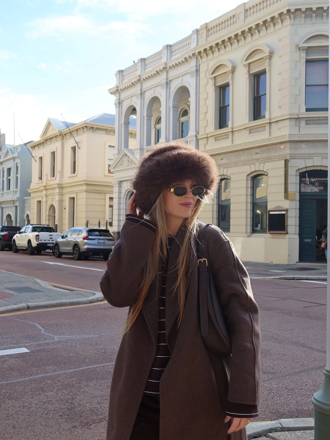 Long dark brown coat with oversized textured hat and striped knit