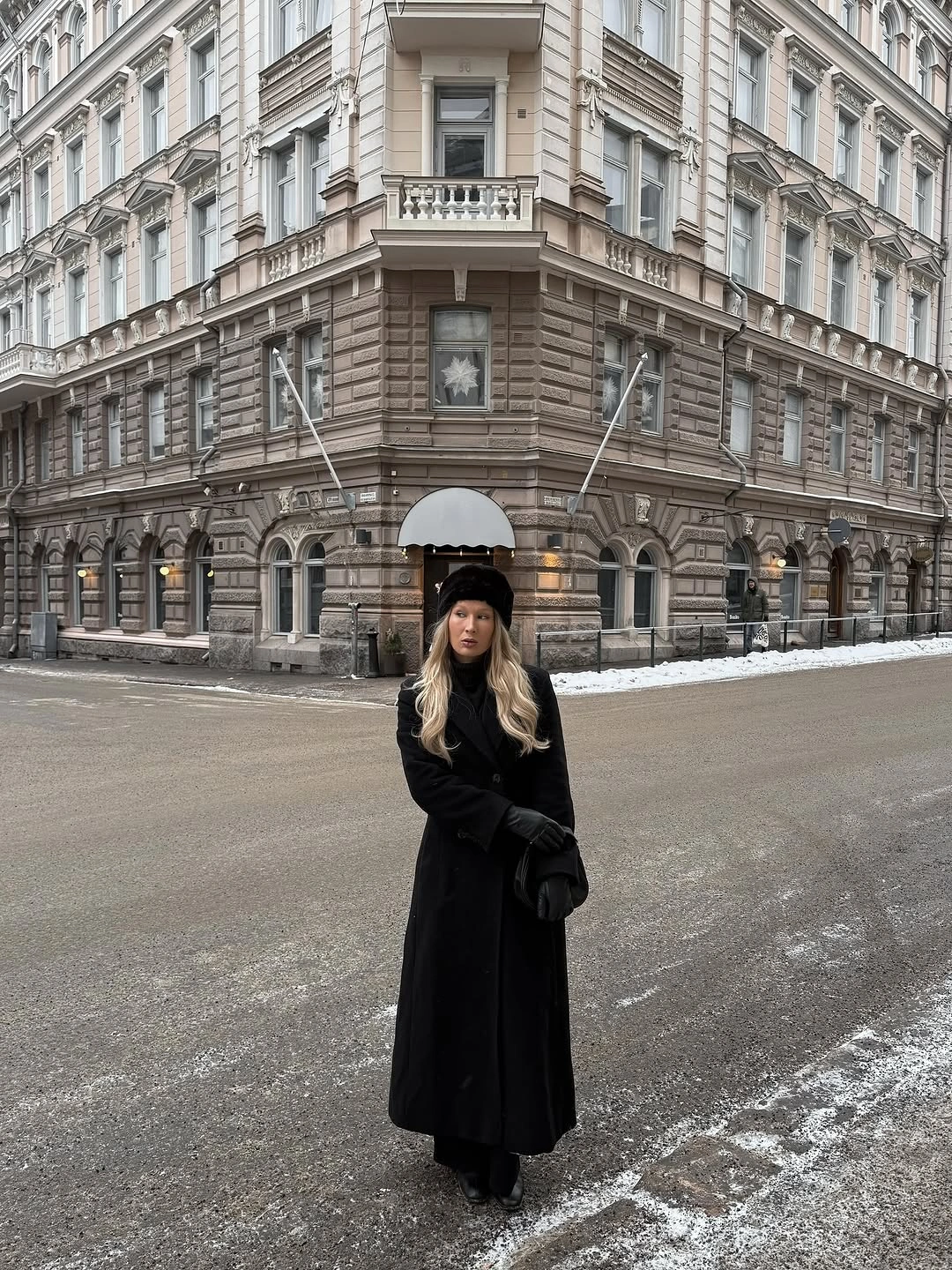 Long black coat with black knit hat and dark winter accessories