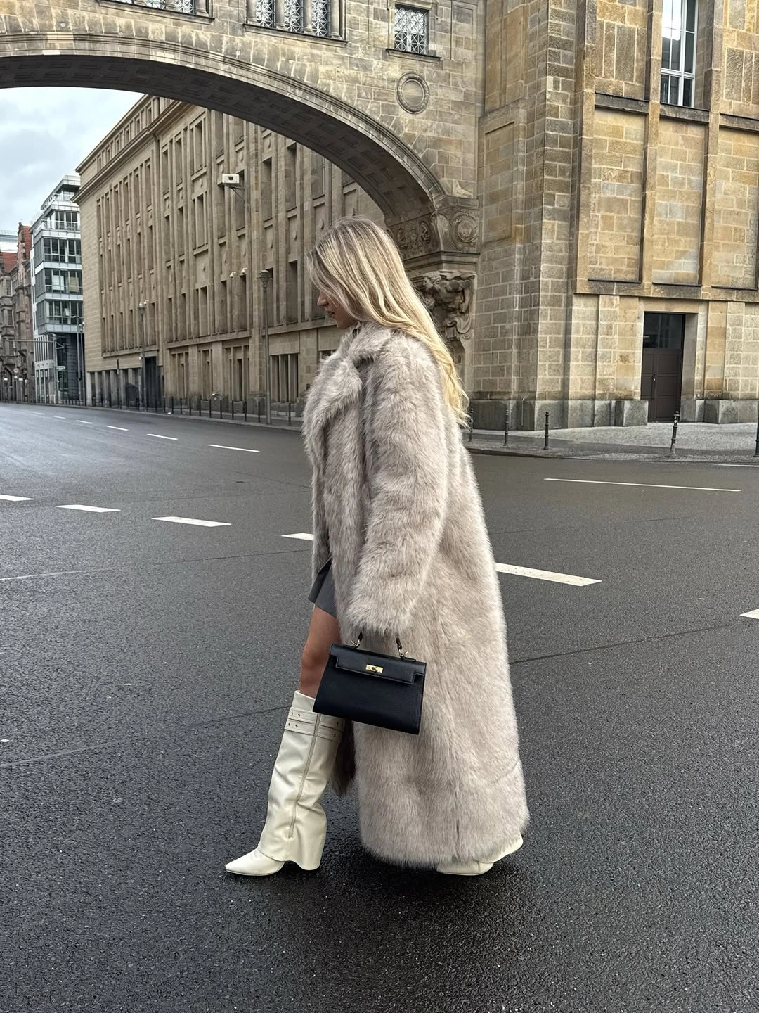 Pale gray-beige long textured coat with white knee boots and black bag