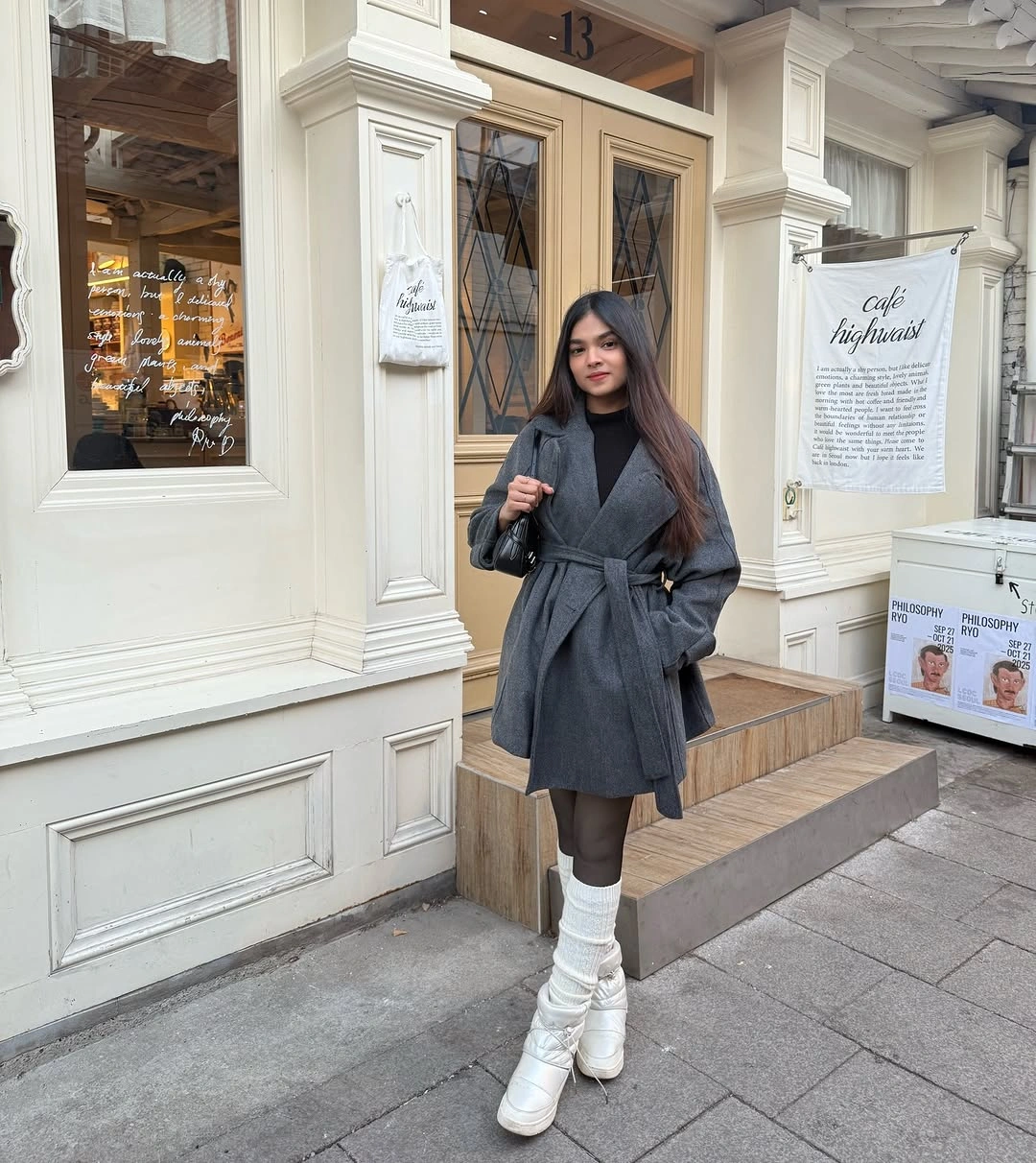 Belted gray coat with black turtleneck and white slouch boots