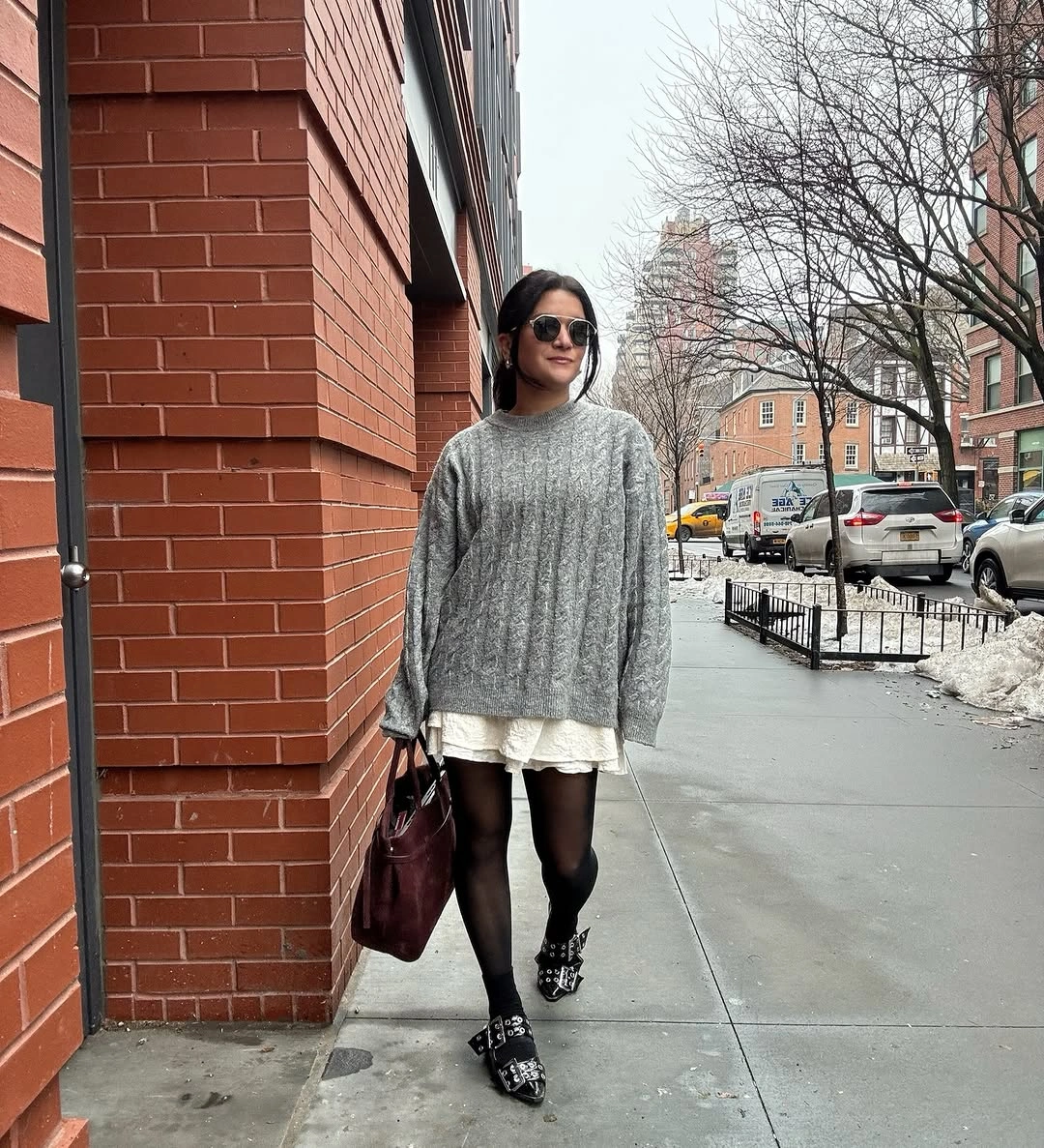 Oversized gray ribbed sweater over pale short hem with black tights