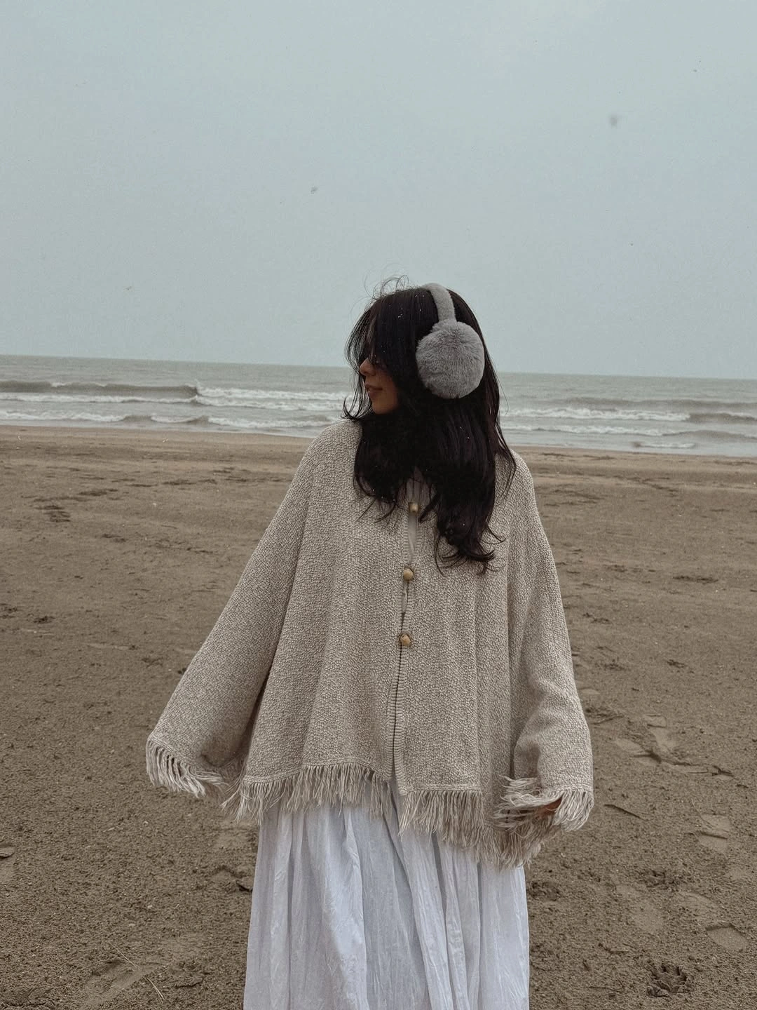 Cream fringed knit layer over long white skirt with soft earmuffs