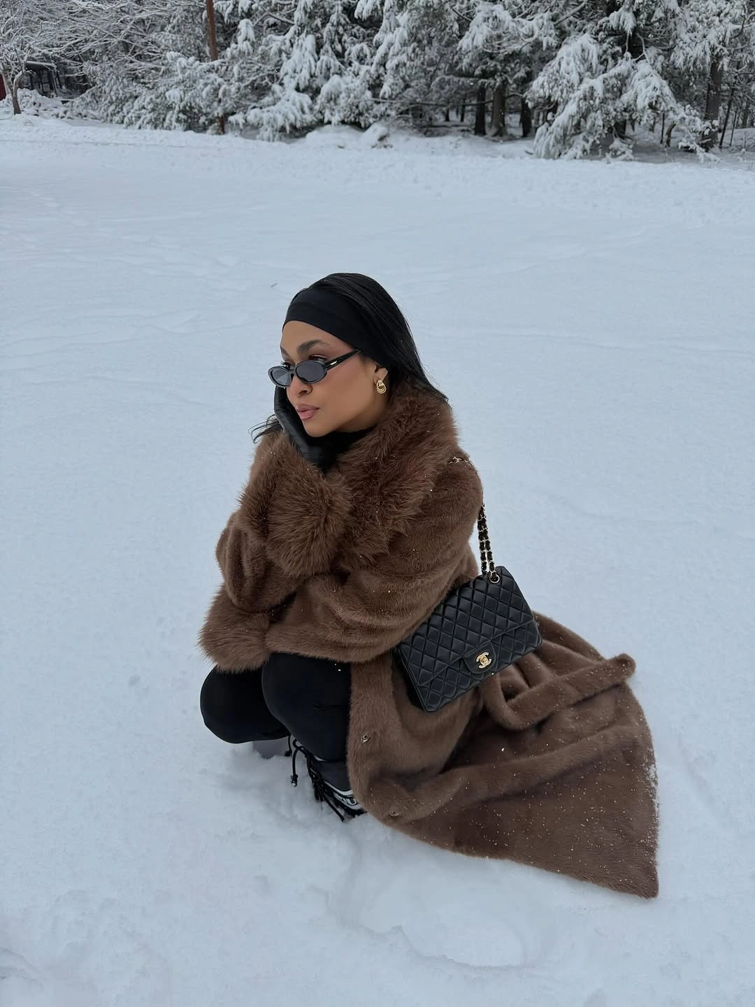 Long deep brown textured coat over black layers with quilted chain bag