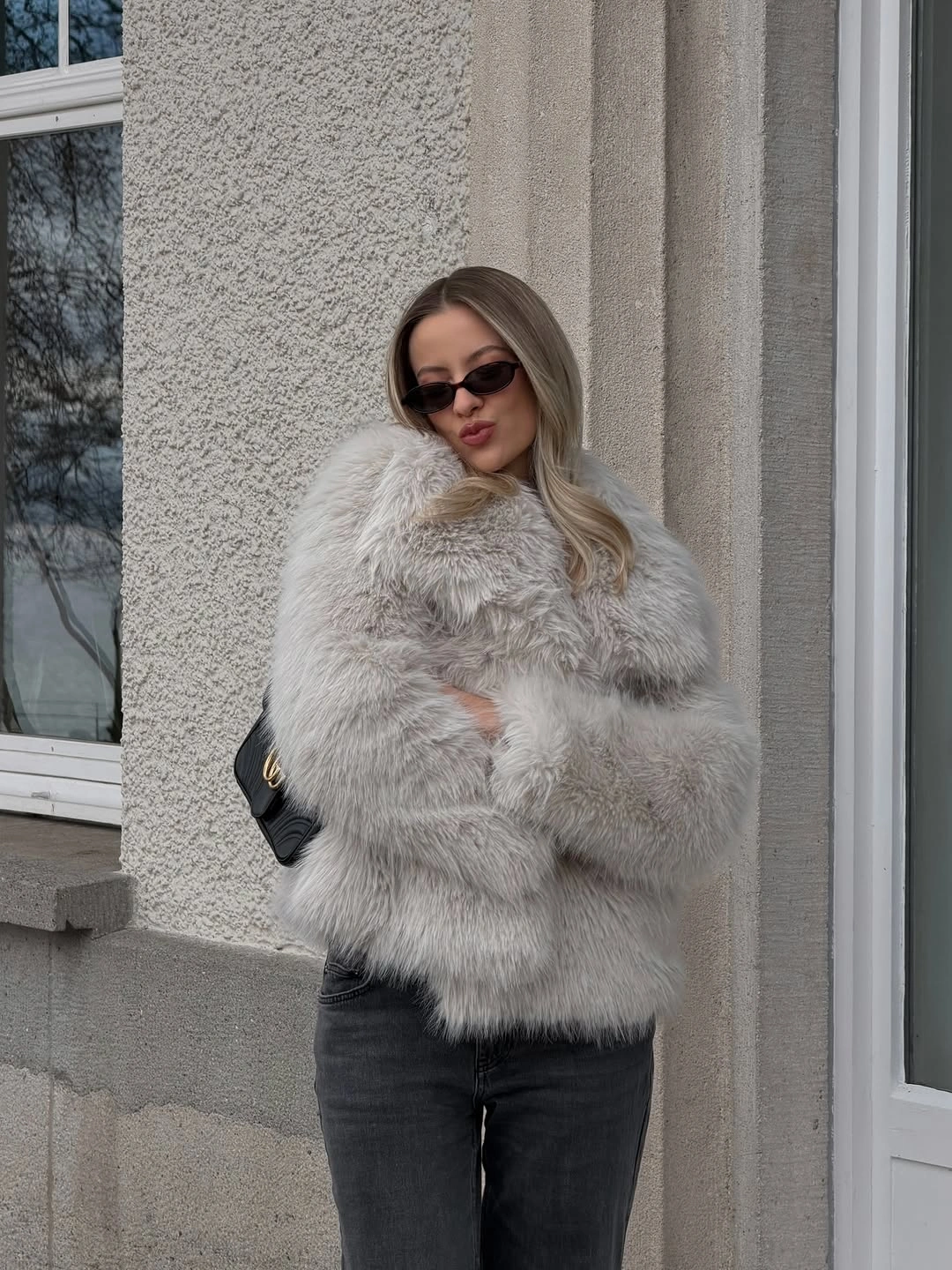 Pale gray shaggy-looking jacket with dark jeans and black bag