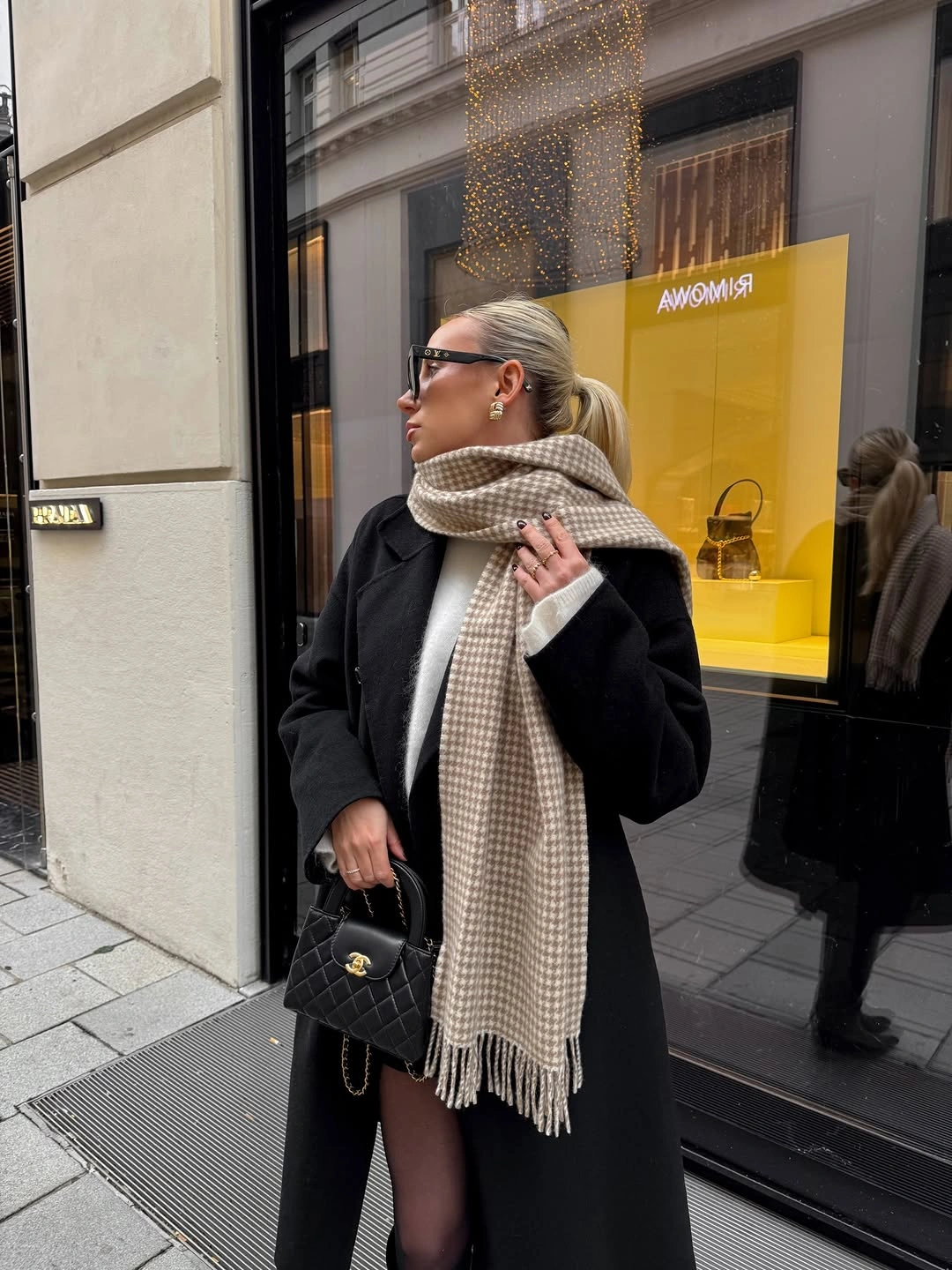 Long black coat with oversized checked scarf sheer tights and handbag