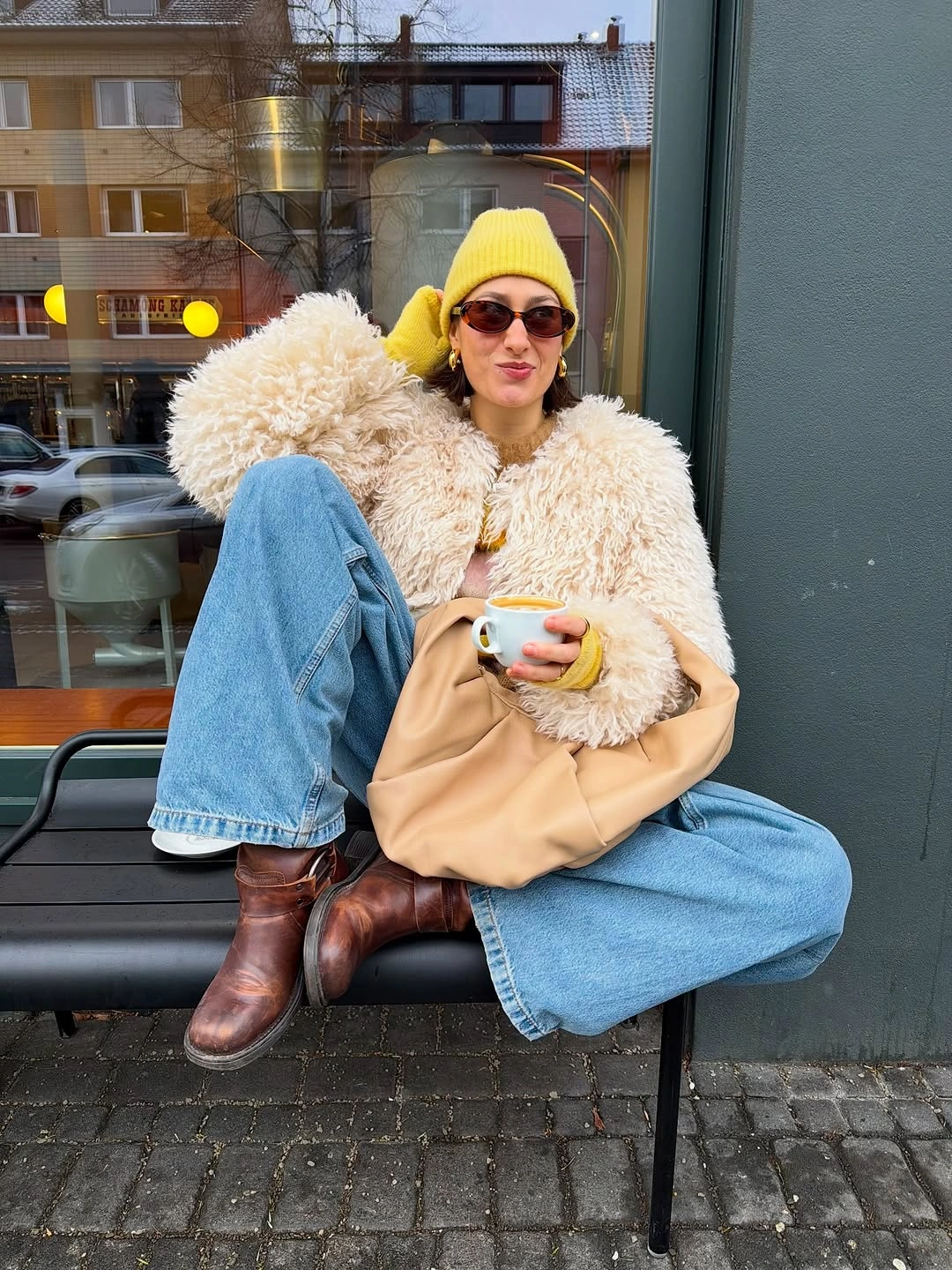 Cream curly-textured jacket blue jeans yellow hat gloves and brown boots
