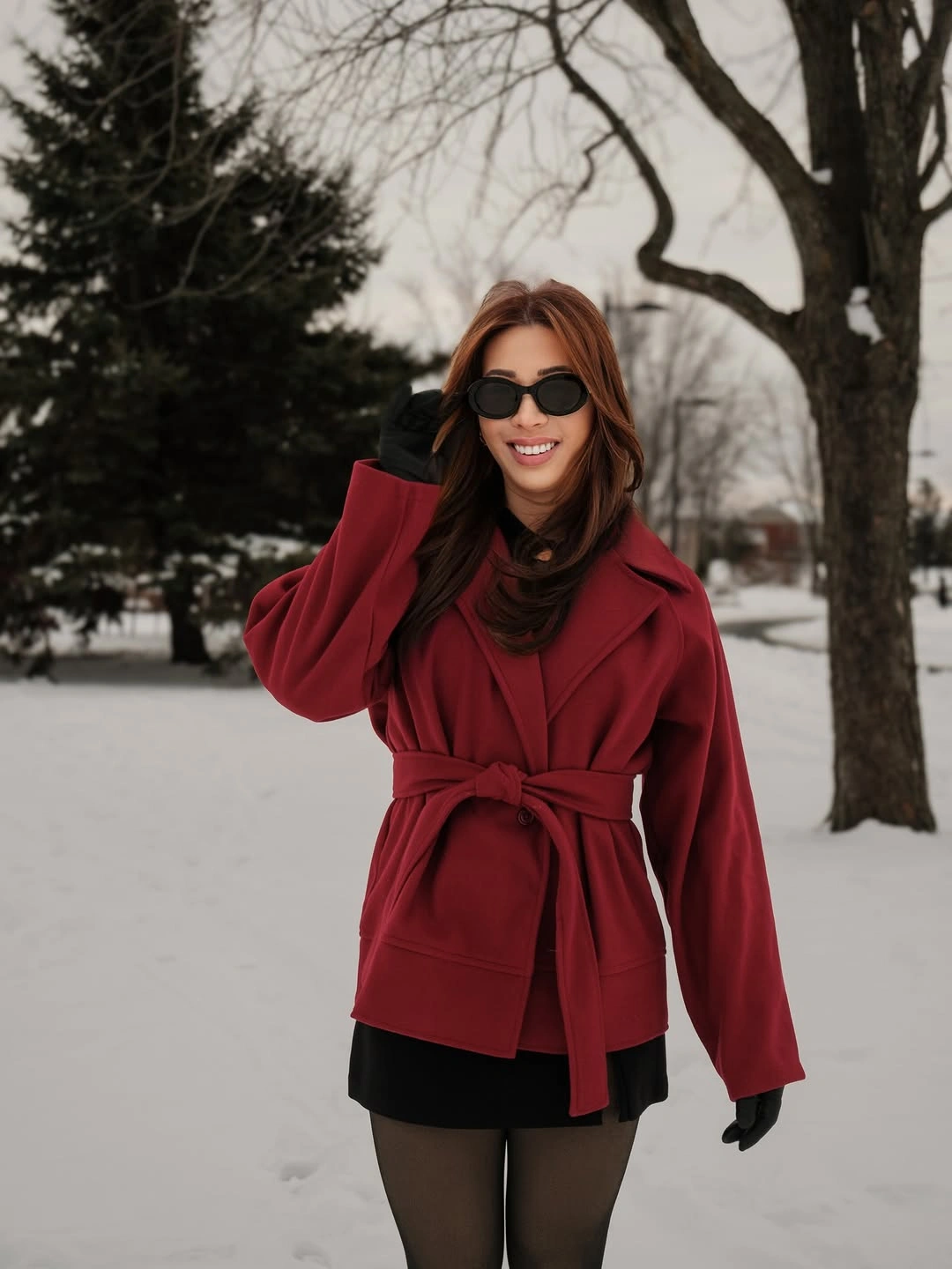 Deep red belted coat with black layers and sheer dark tights