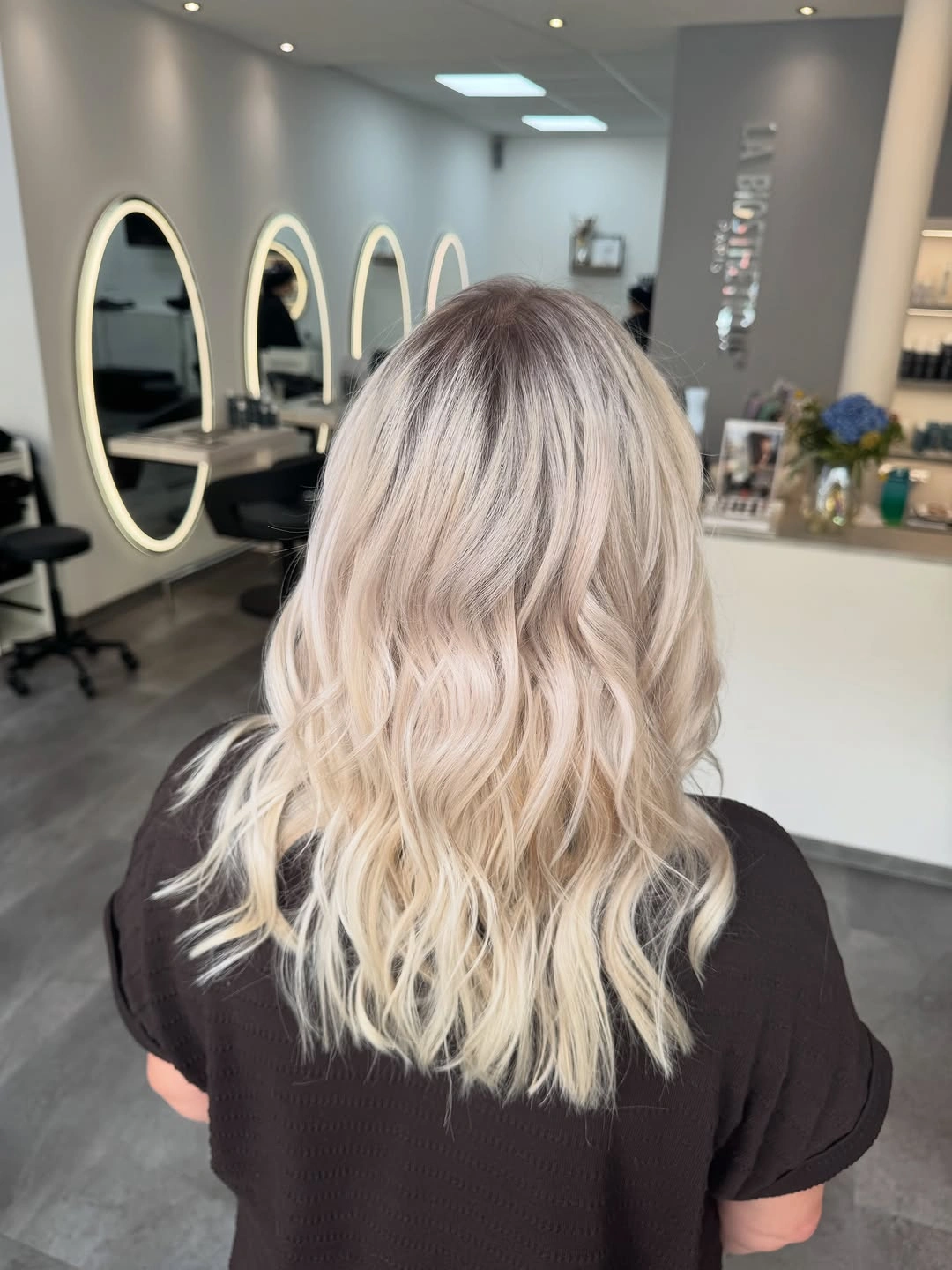Shoulder length wavy blonde hair with smoky darker roots