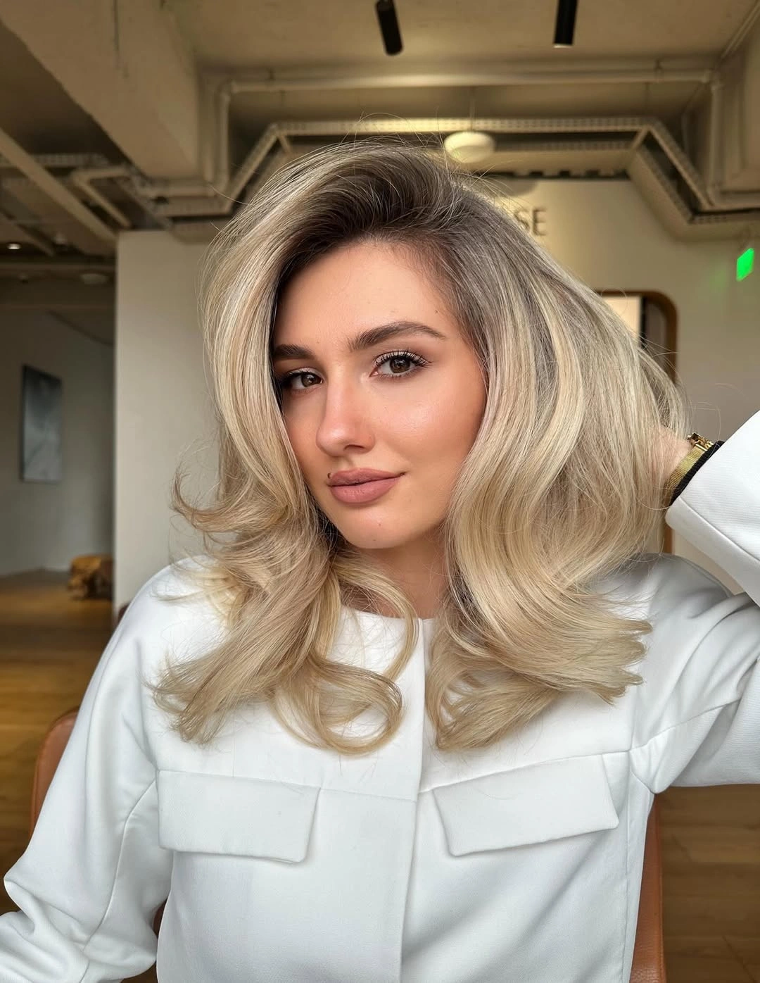 Voluminous champagne blonde hair with curled ends and side sweep