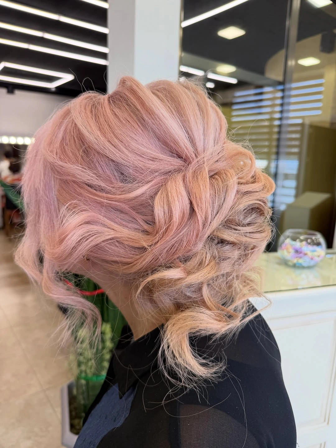 Rose-blonde low updo with curled face-framing pieces