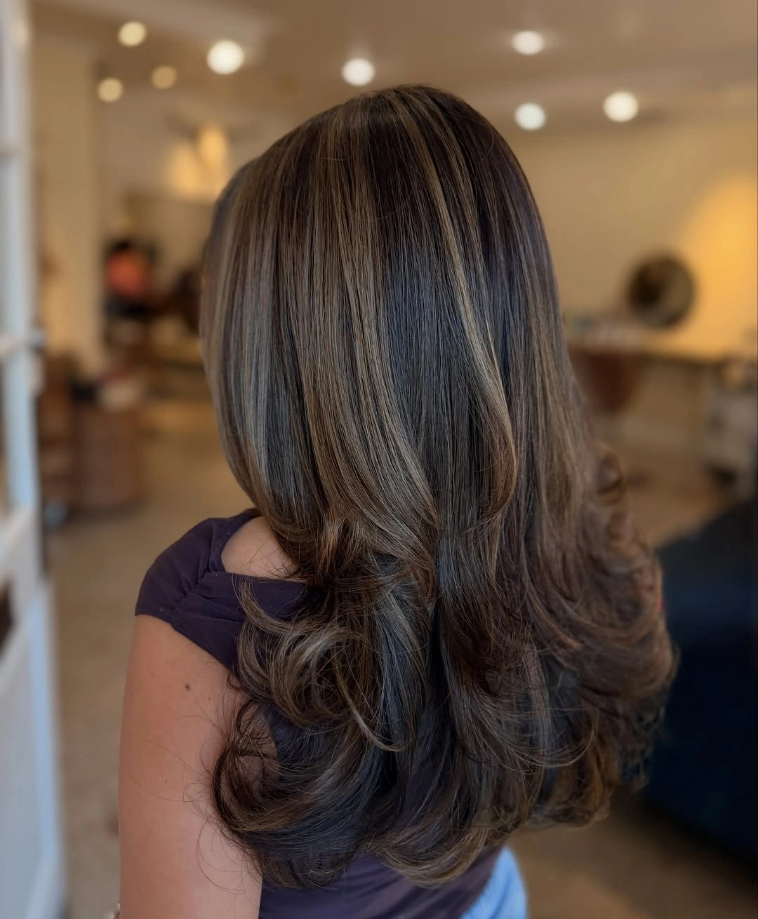 Long brunette layered hair with caramel ribbons and curled ends