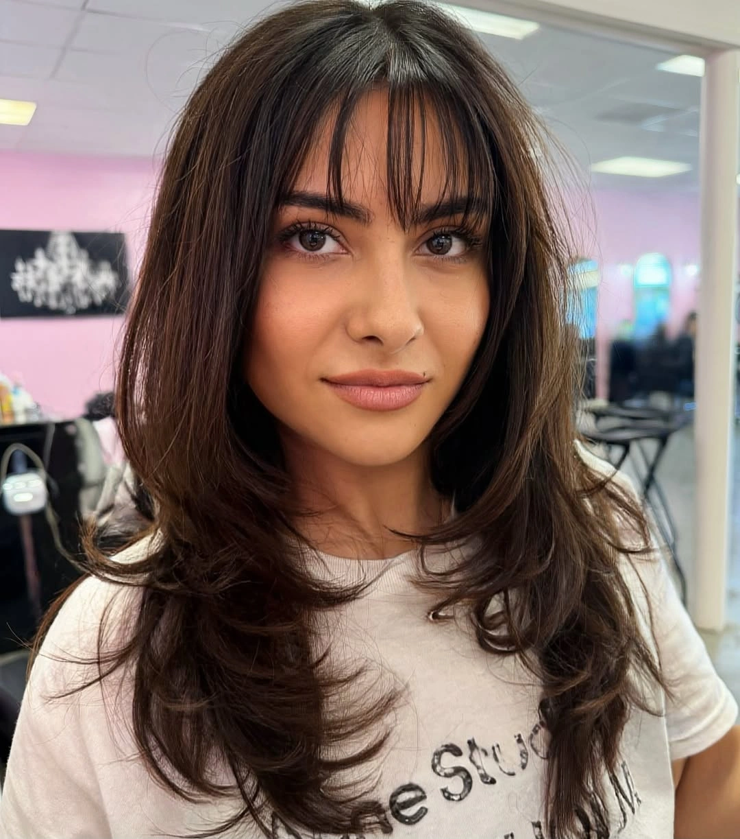 Brunette layered haircut with wispy bangs and flipped ends