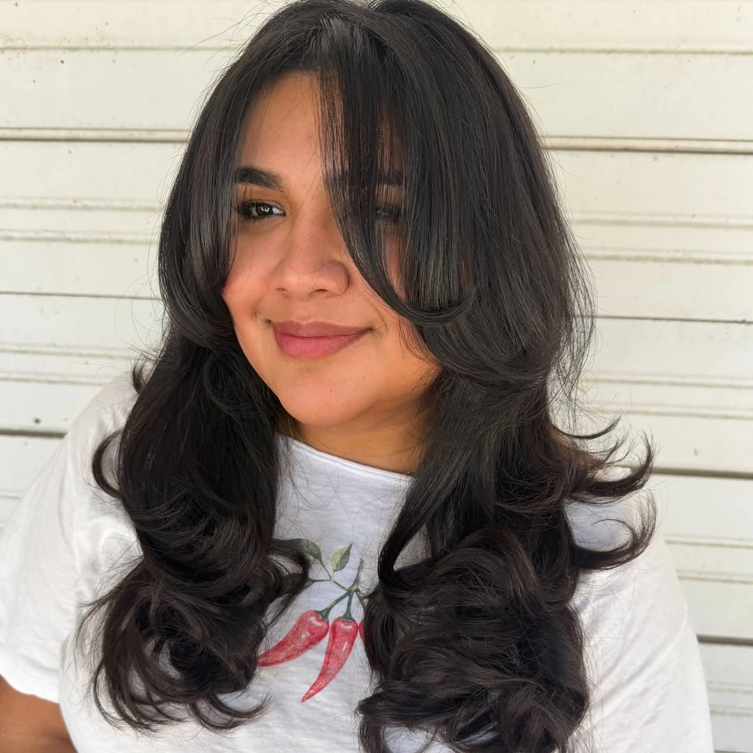 Dark layered hair with curtain bangs and curled ends