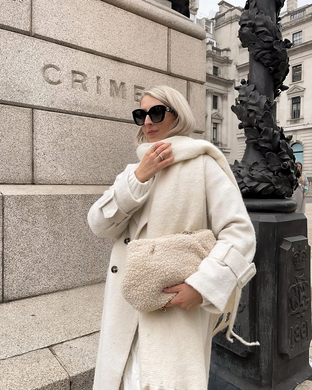 Off-white long coat with cream scarf and textured clutch