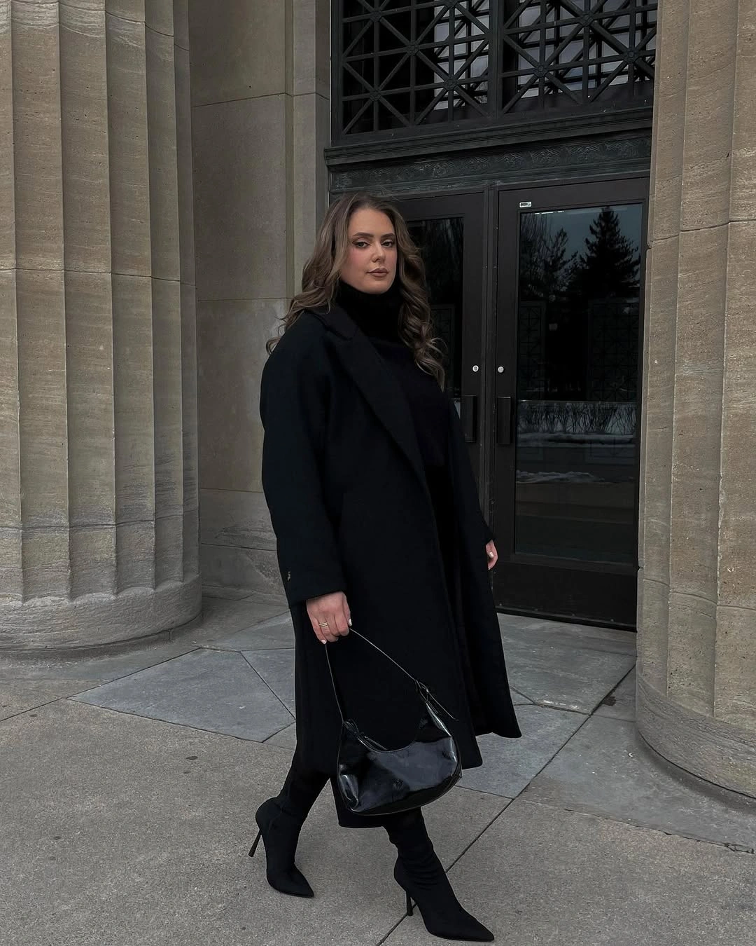 Long black coat with high neck and pointed boots