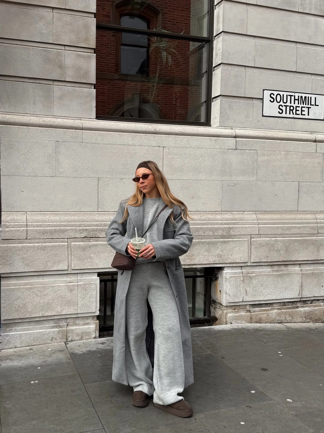 Long gray coat with wide gray trousers and brown accents