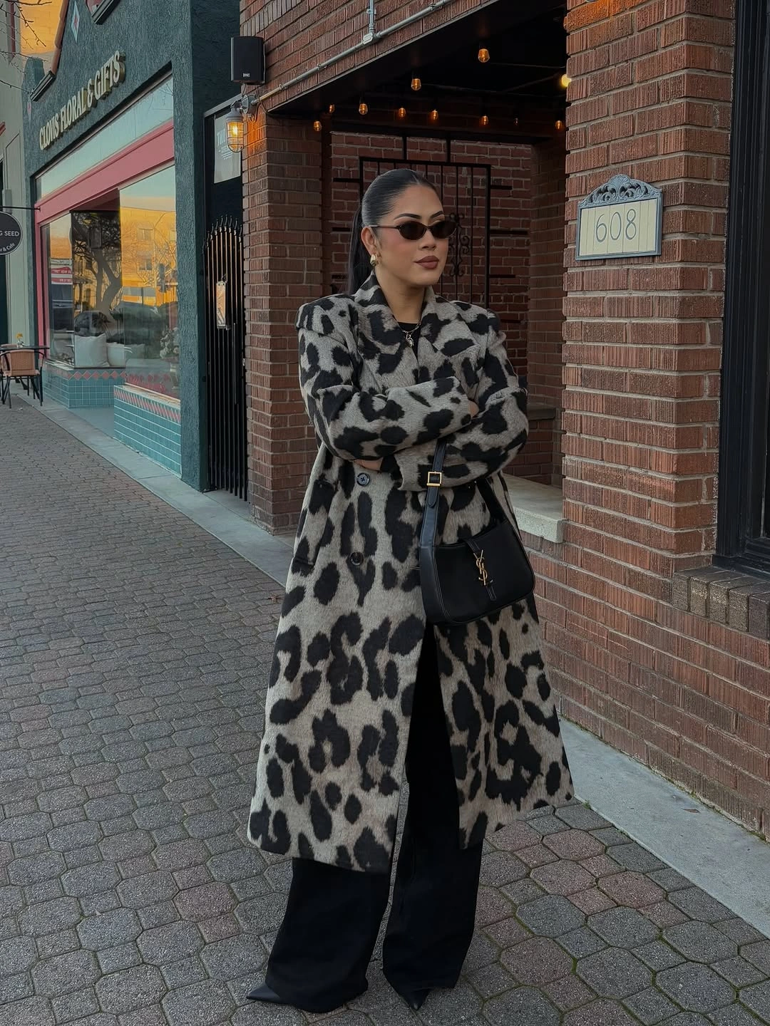 Long patterned coat with wide black trousers and shoulder bag