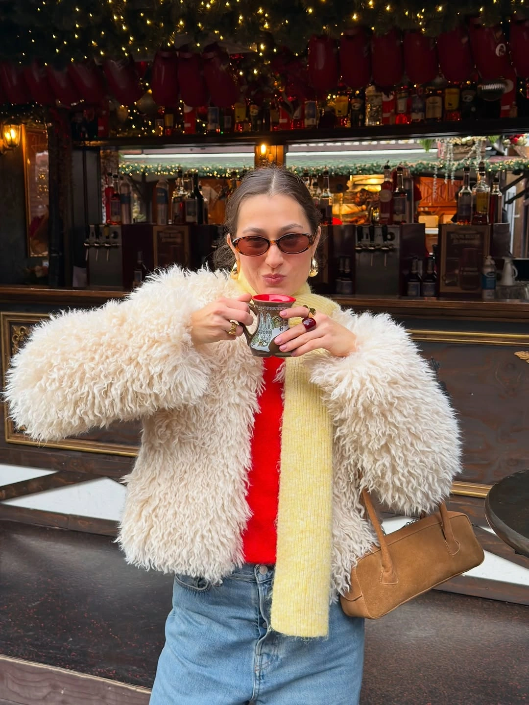 Cream textured jacket with red top, yellow scarf, and jeans