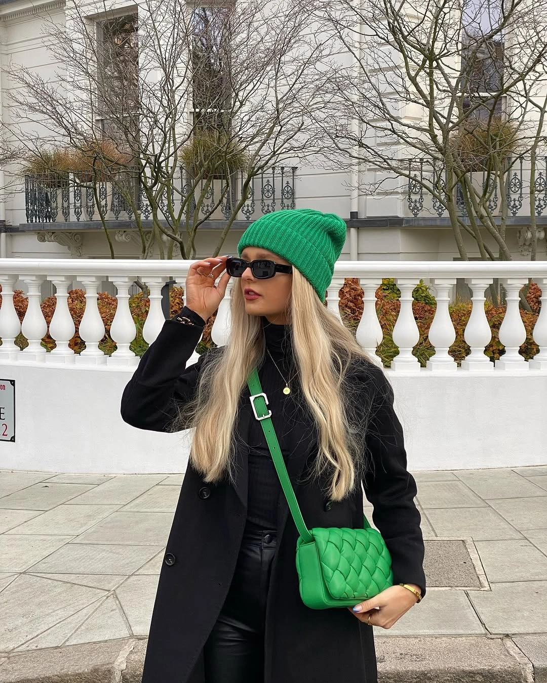 Black long coat with green beanie and bag