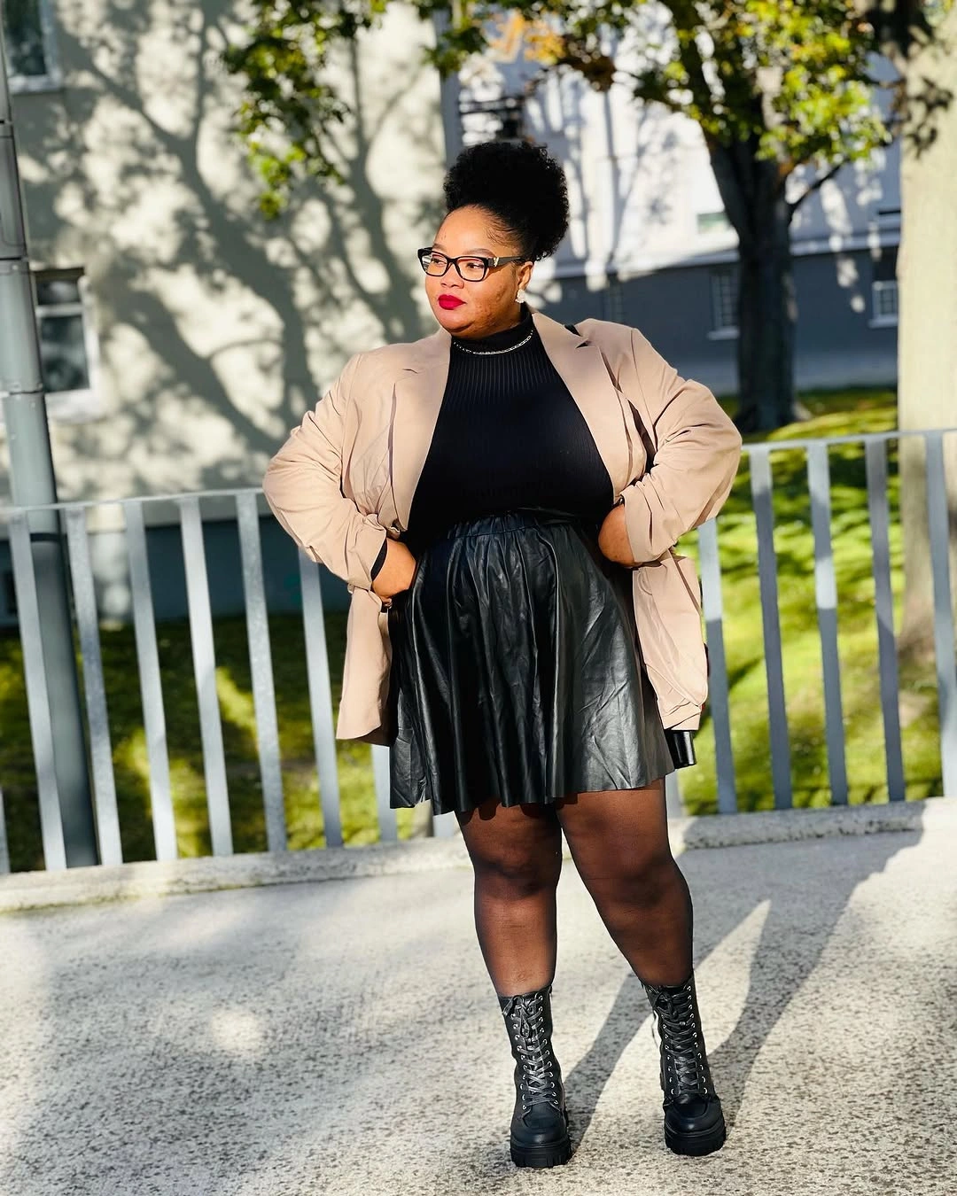 Beige blazer with black top, skirt, and boots