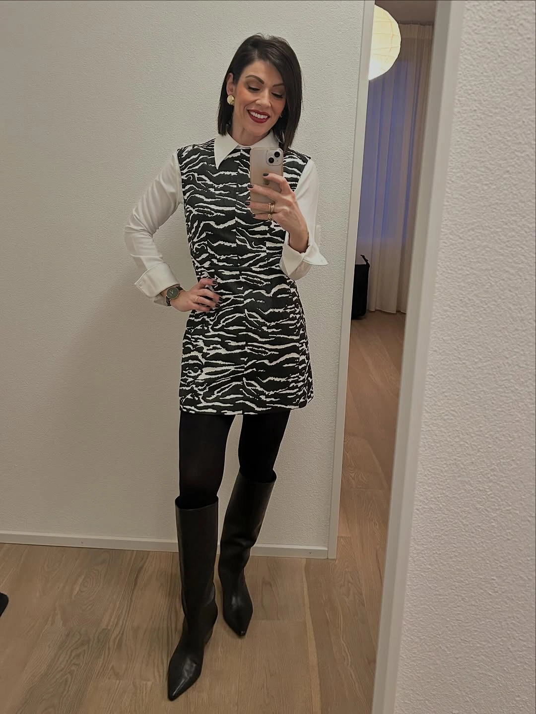 Zebra-pattern sleeveless dress over white blouse with black boots