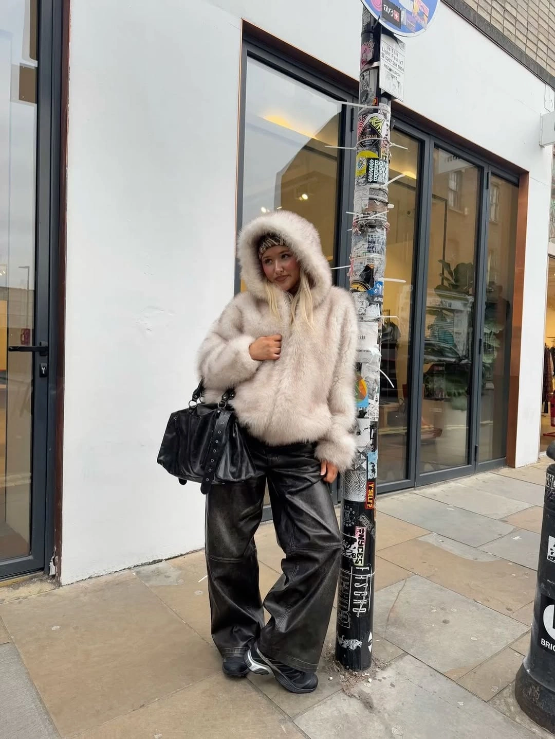 Fluffy cream hooded coat with black leather pants and handbag