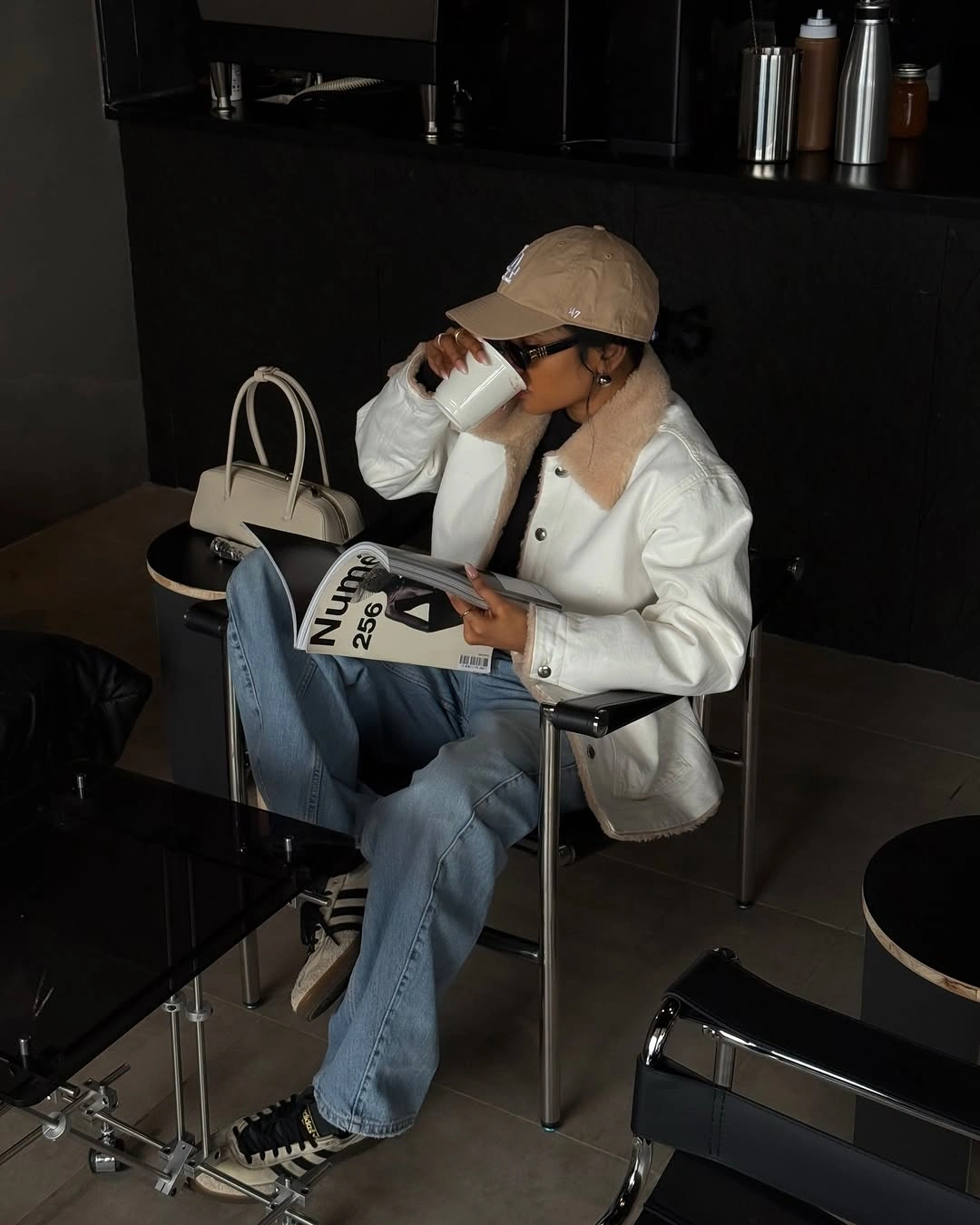 White jacket with beige cap, light jeans and white bag