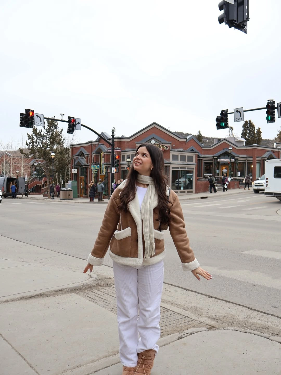 Brown shearling-style jacket with white pants and tan boots