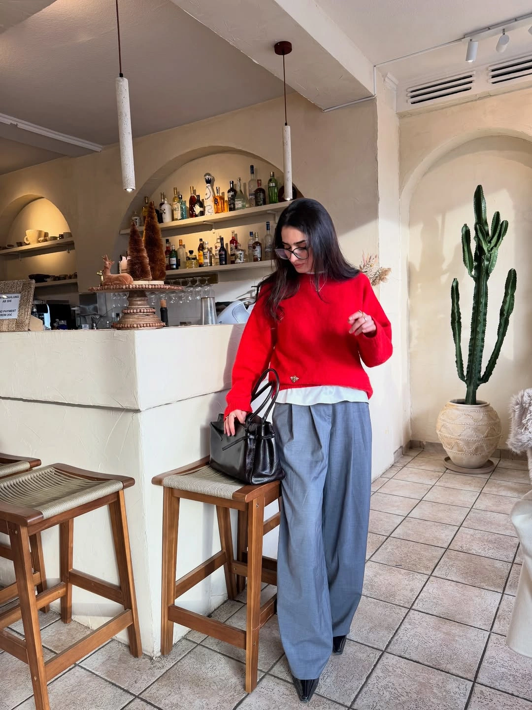 Red sweater with wide grey trousers and black handbag