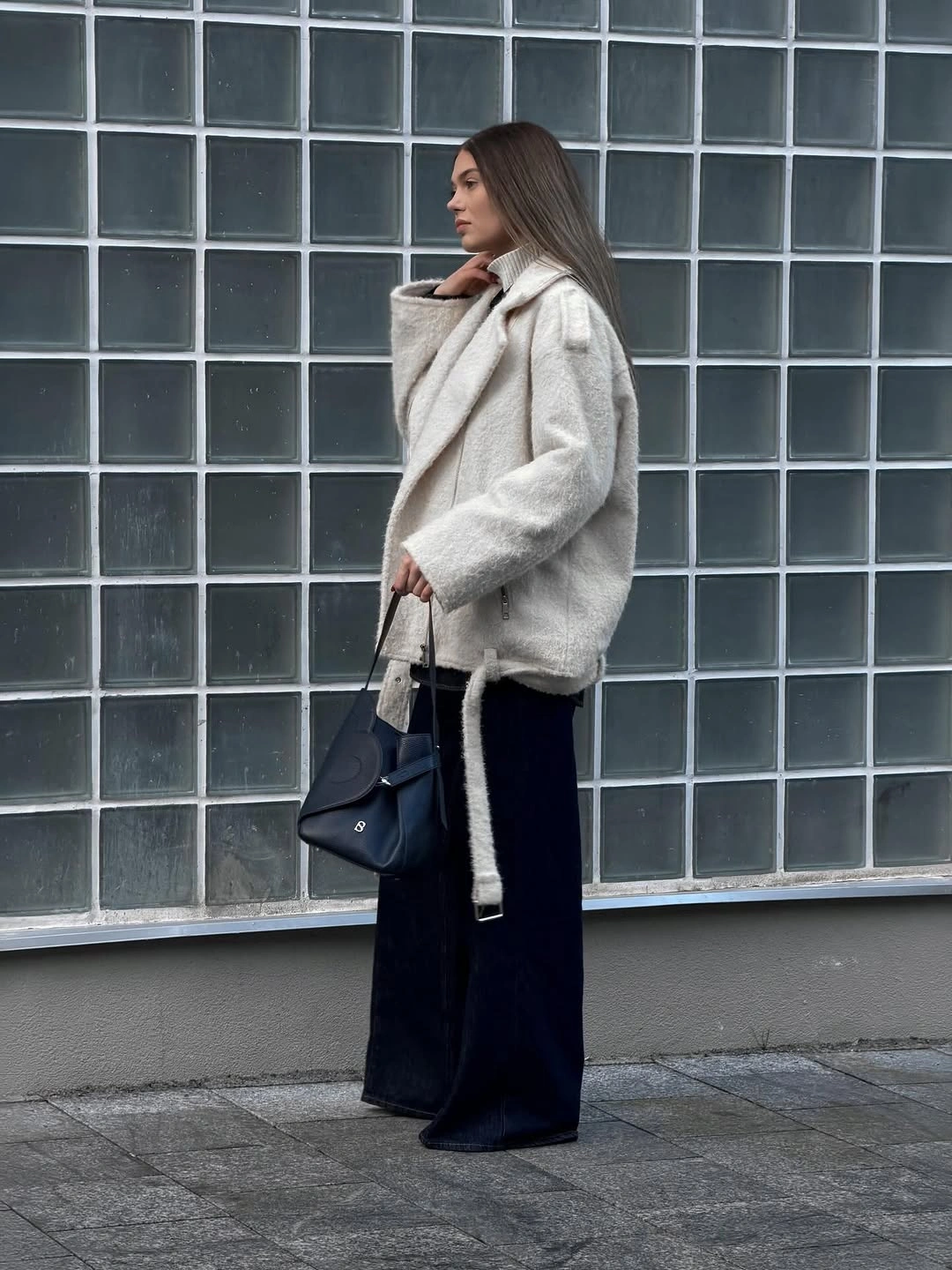 Light gray textured jacket with dark flared trousers and black tote