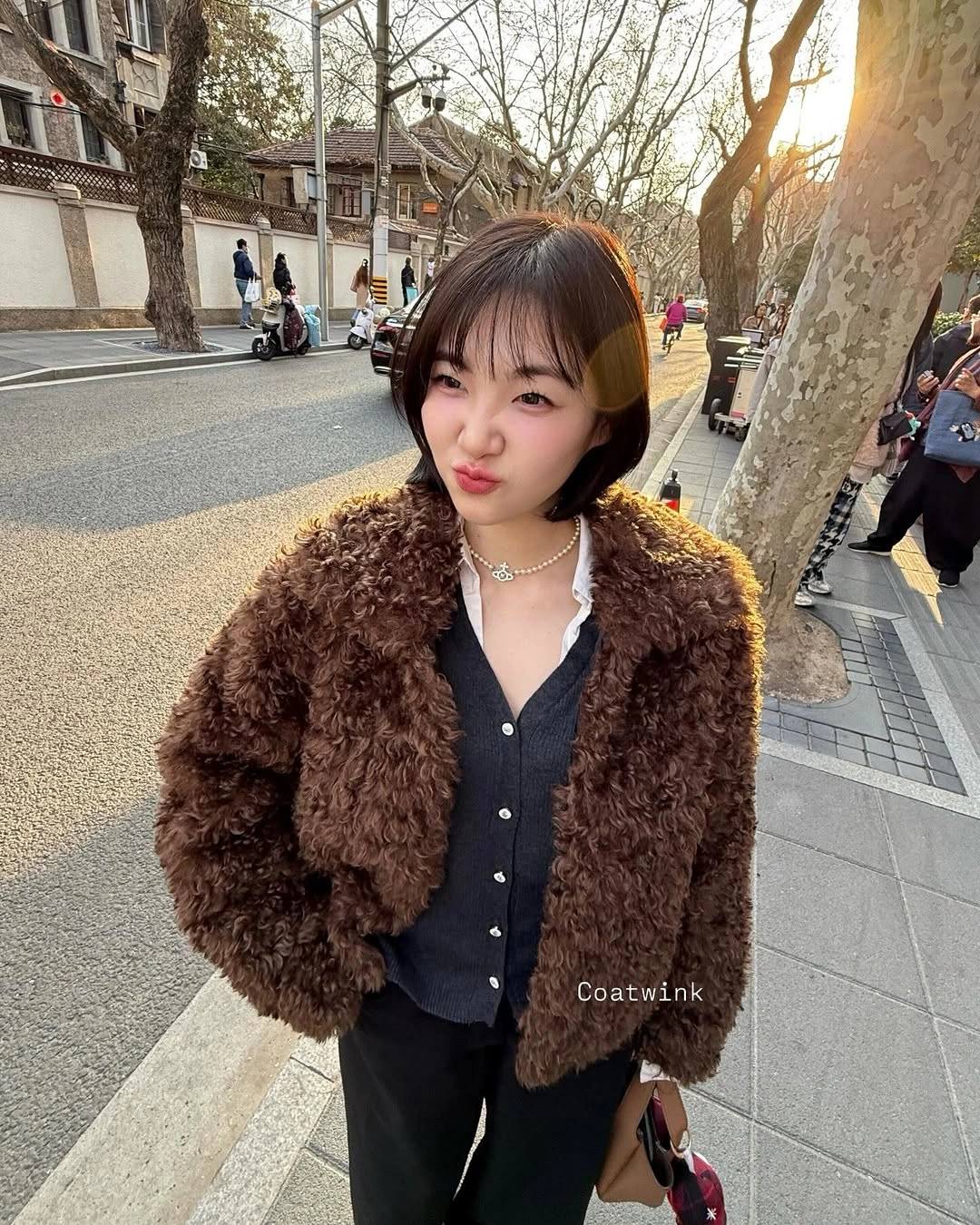 Short brown textured jacket over black top and trousers