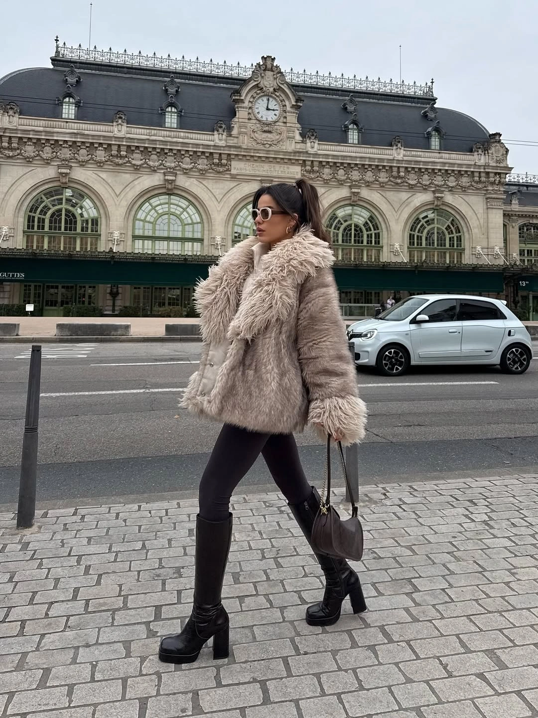Beige shaggy short coat with black tights ankle boots and dark handbag