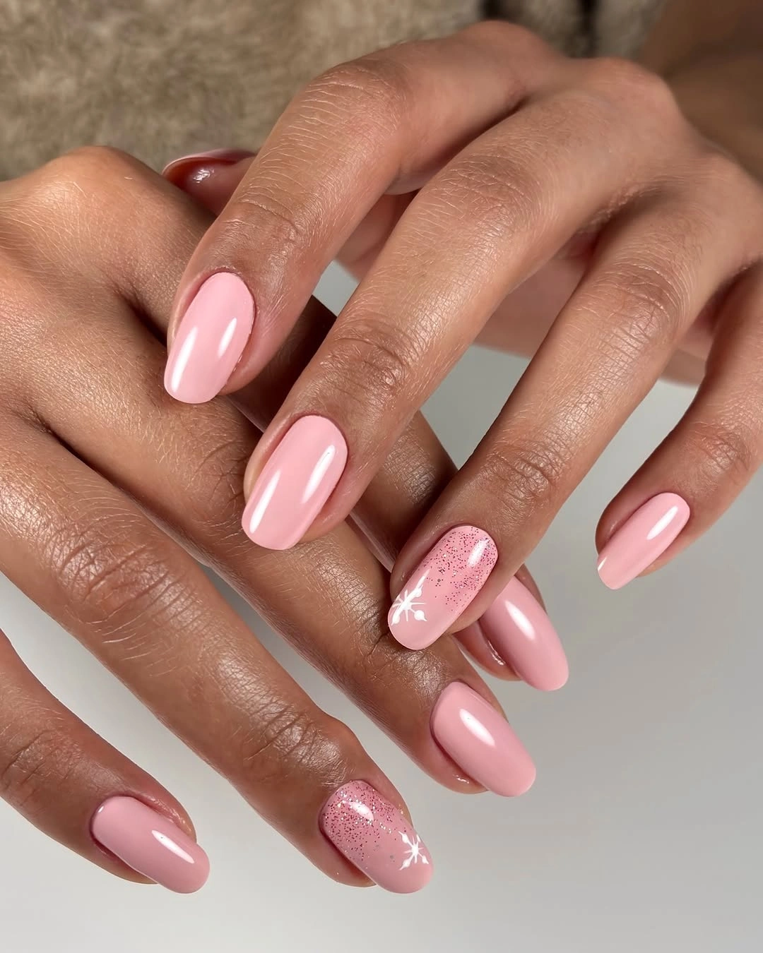 Soft pink almond nails with tiny white snowflake accents