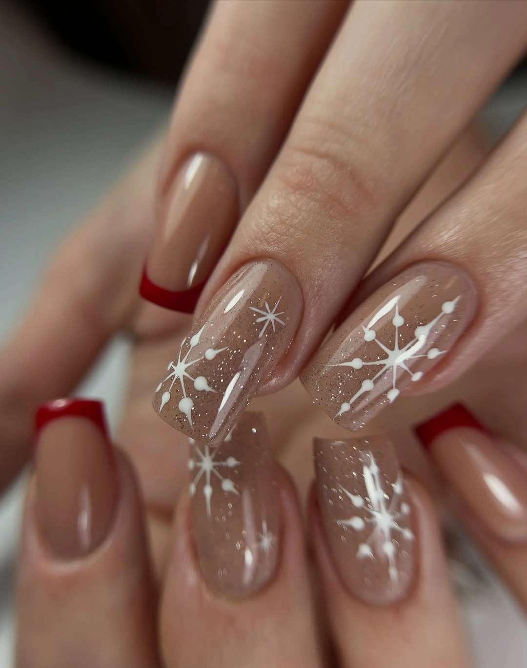 Nude nails with red French tips and white star details