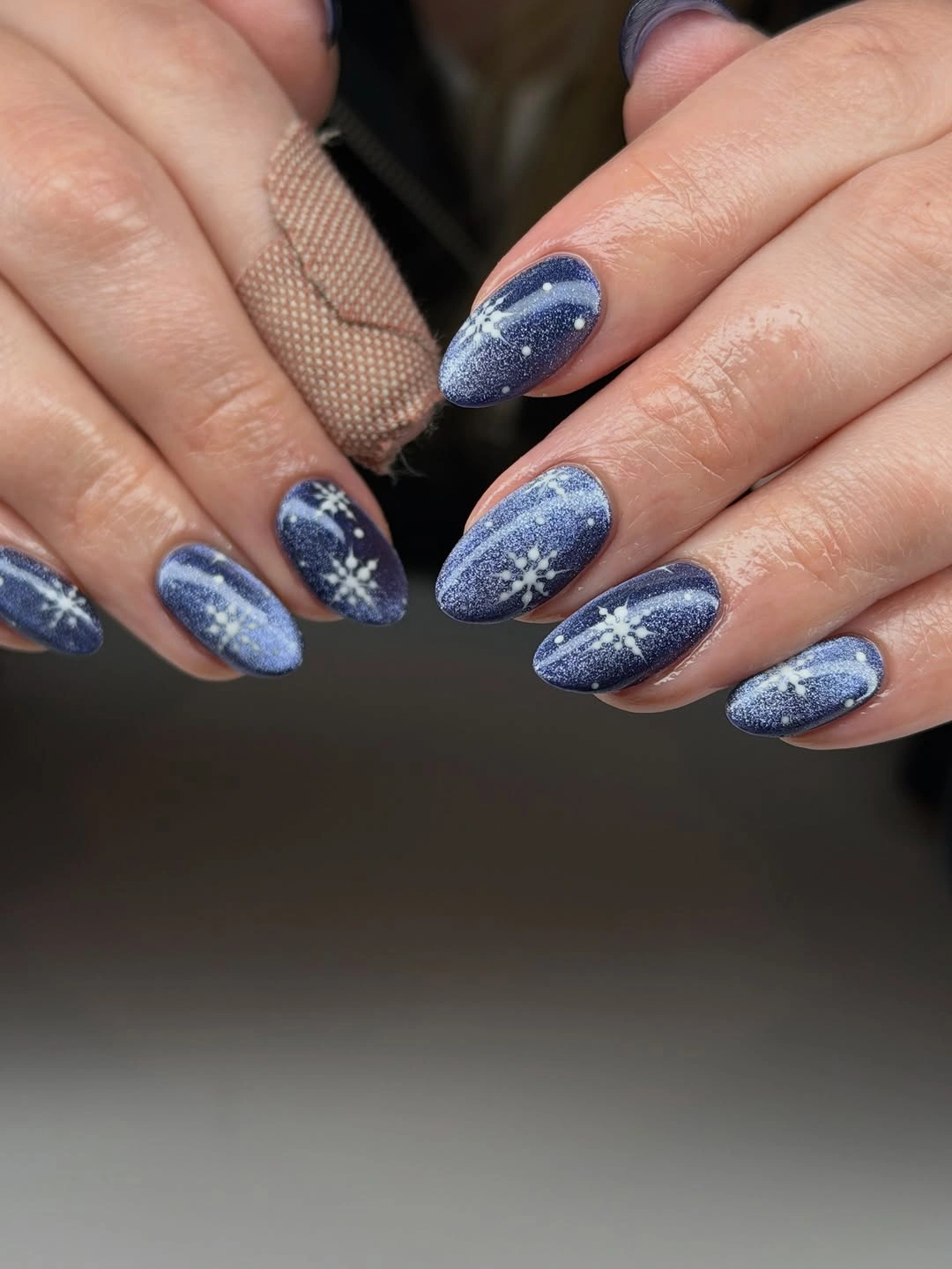 Blue shimmer almond nails with white snowflake and speckled details