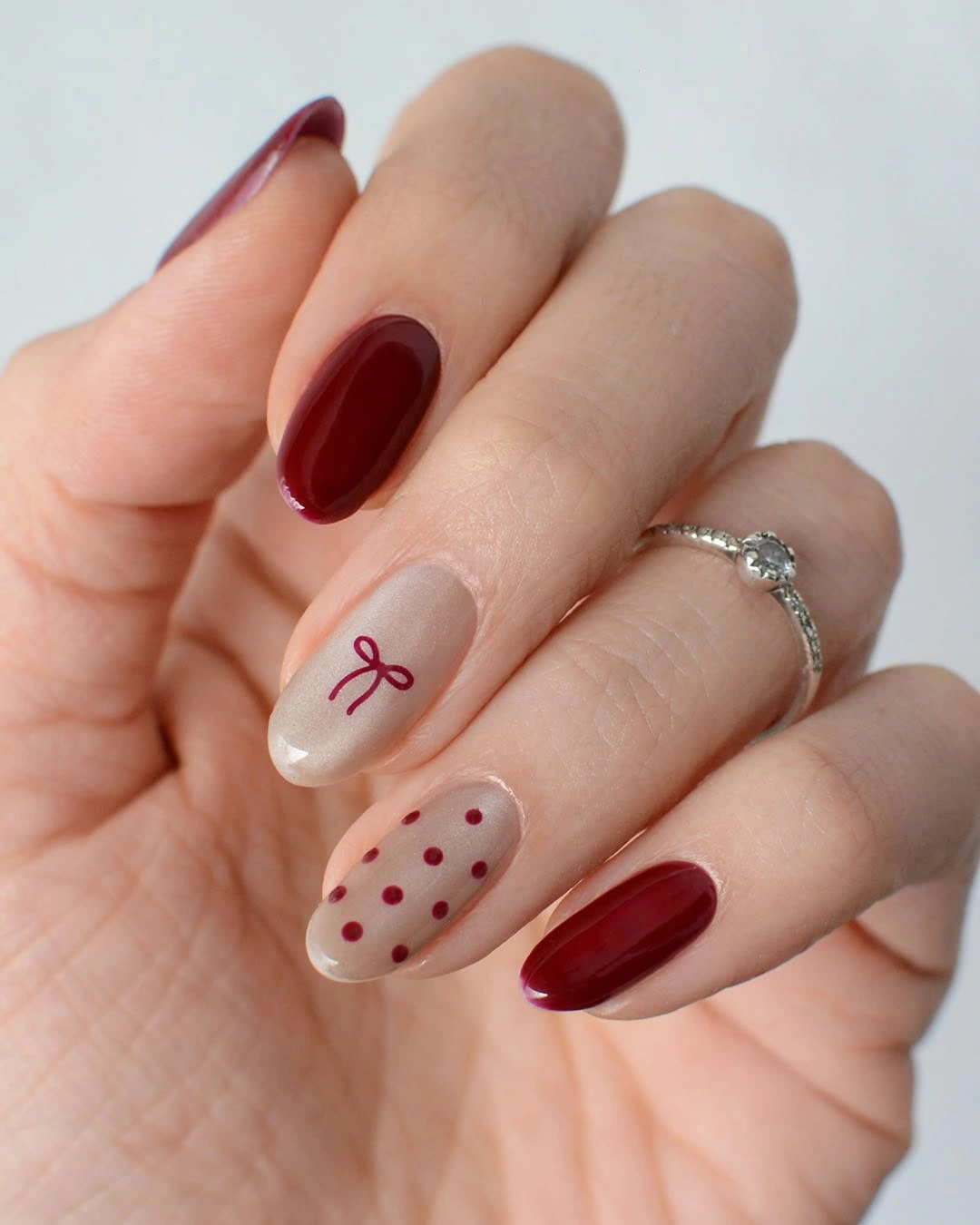 Glossy red and nude nails with bow and polka dots