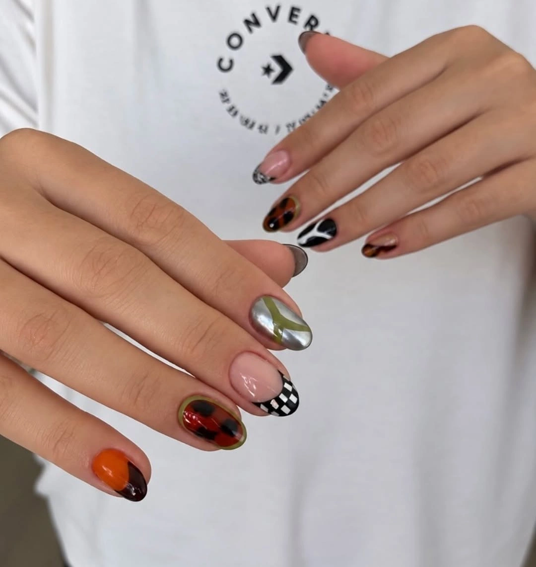 Mismatched short nails with orange, checks, swirls and tortoiseshell accents