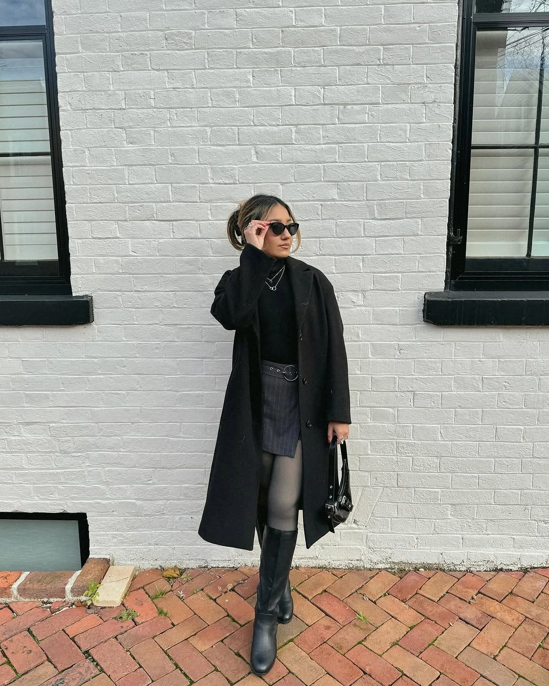 Long black coat, charcoal mini skirt, sheer tights, and tall boots
