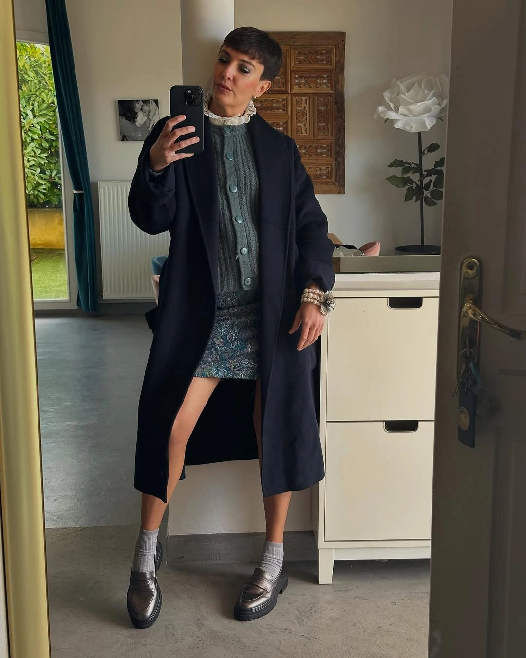 Black turtleneck with olive checked skirt, patch pocket, and waist straps