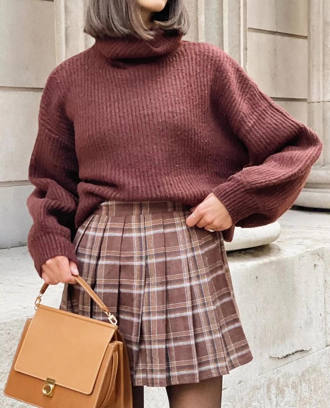 Burgundy turtleneck, brown plaid mini skirt, black tights, and tan handbag