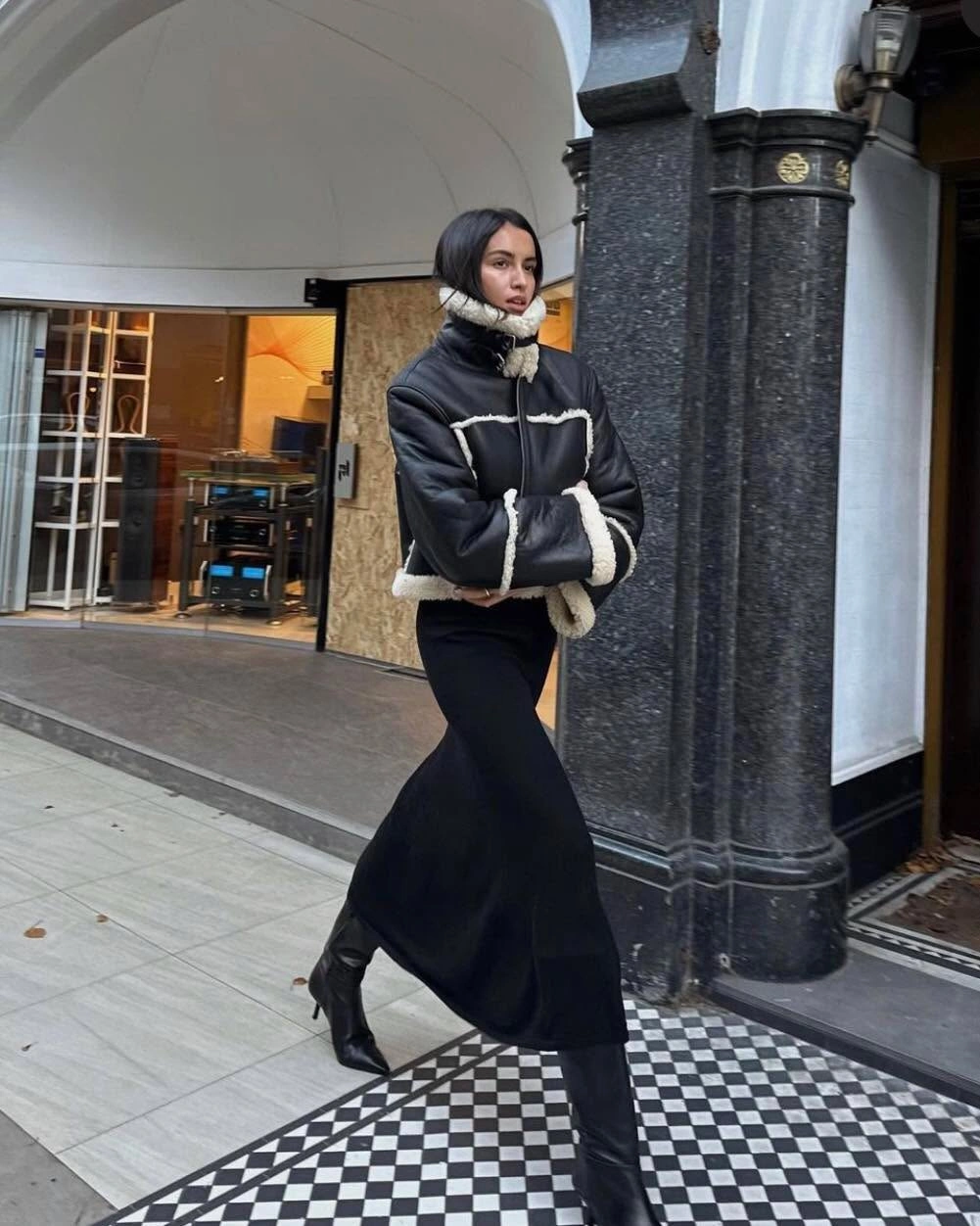 Black padded jacket with pale trim, long skirt, and black boots