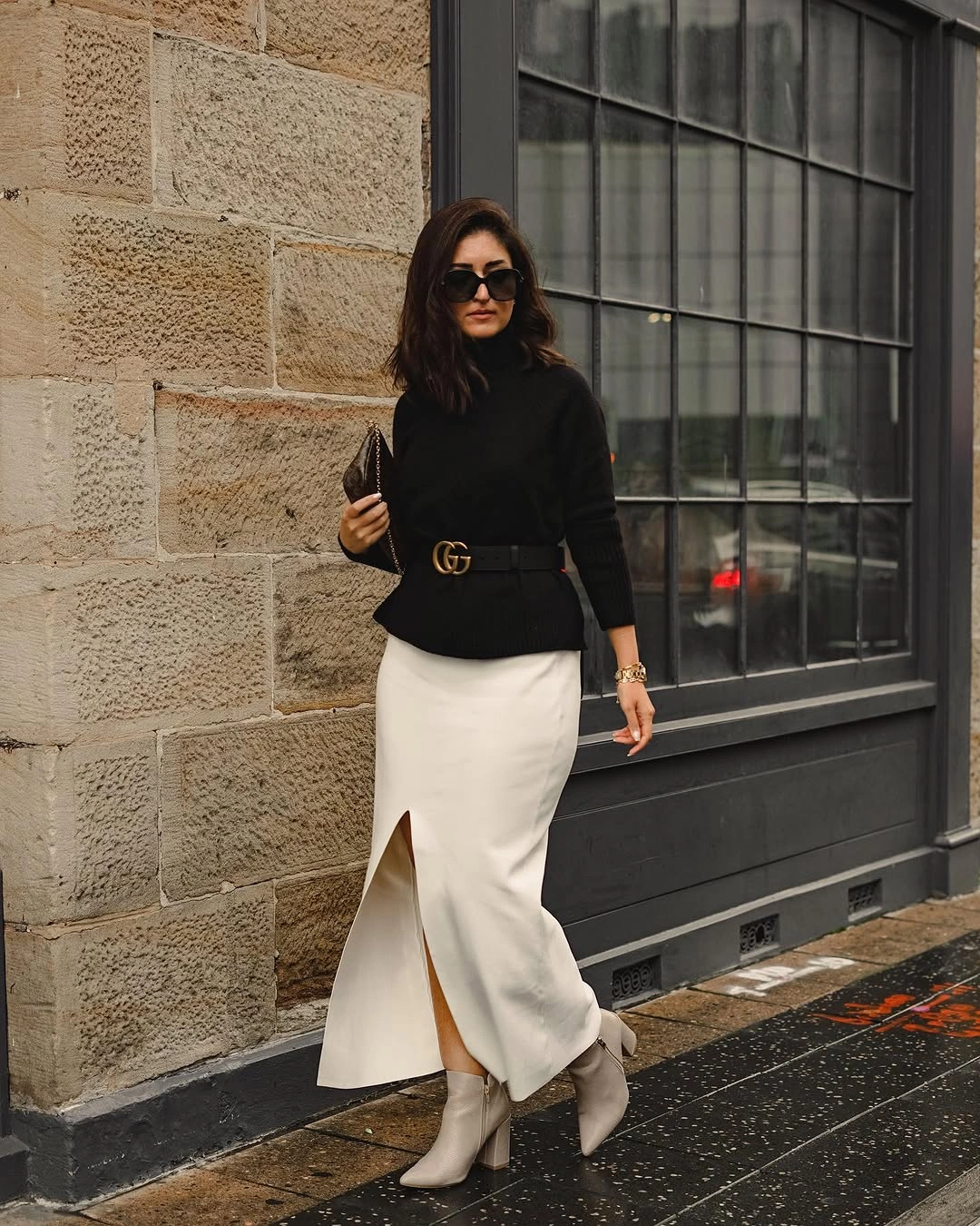 Black turtleneck, cream satin-looking midi skirt, slit, and light ankle boots