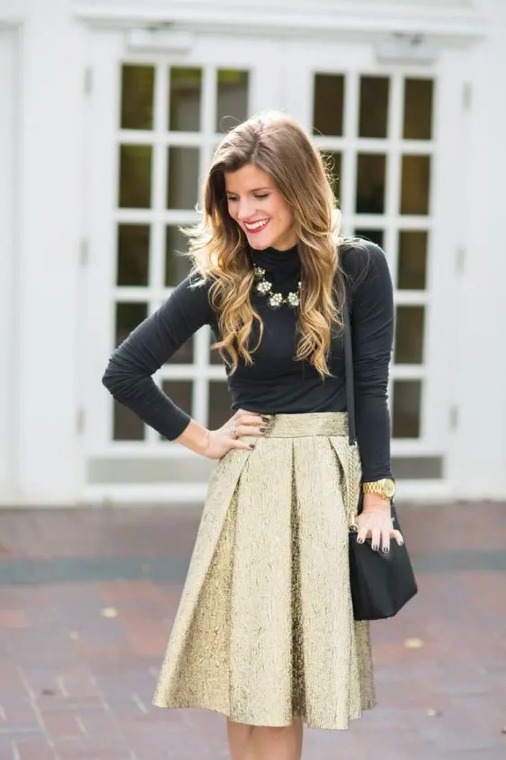 Black Turtleneck with Shimmering Gold Pleated Skirt — Winter Wedding Guest Outfits