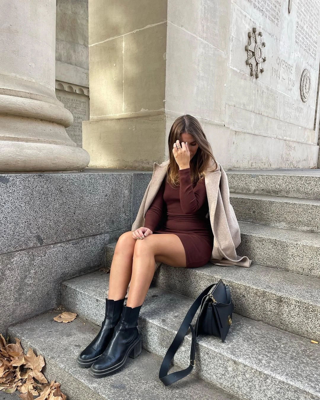 Burgundy mini dress with beige jacket, black ankle boots, and dark handbag