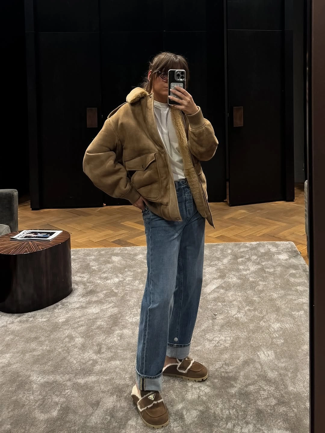 Tan textured jacket, white top, blue jeans, and brown slip-on shoes