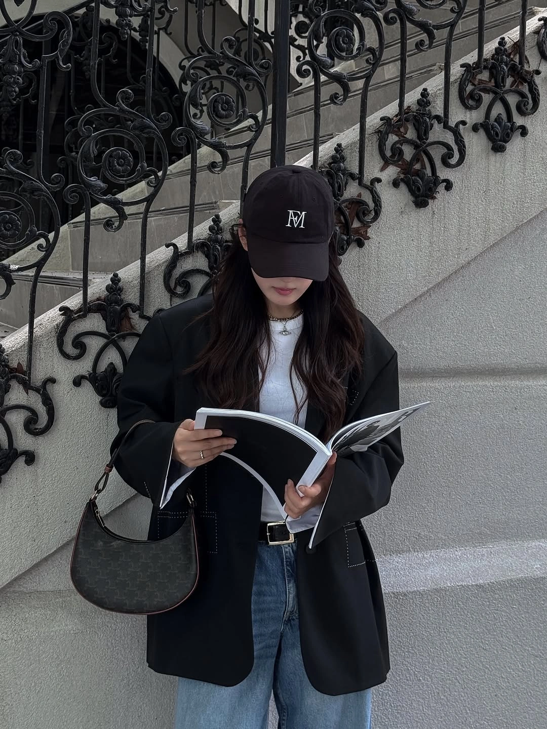Black blazer, white shirt, blue jeans, cap, and curved shoulder bag
