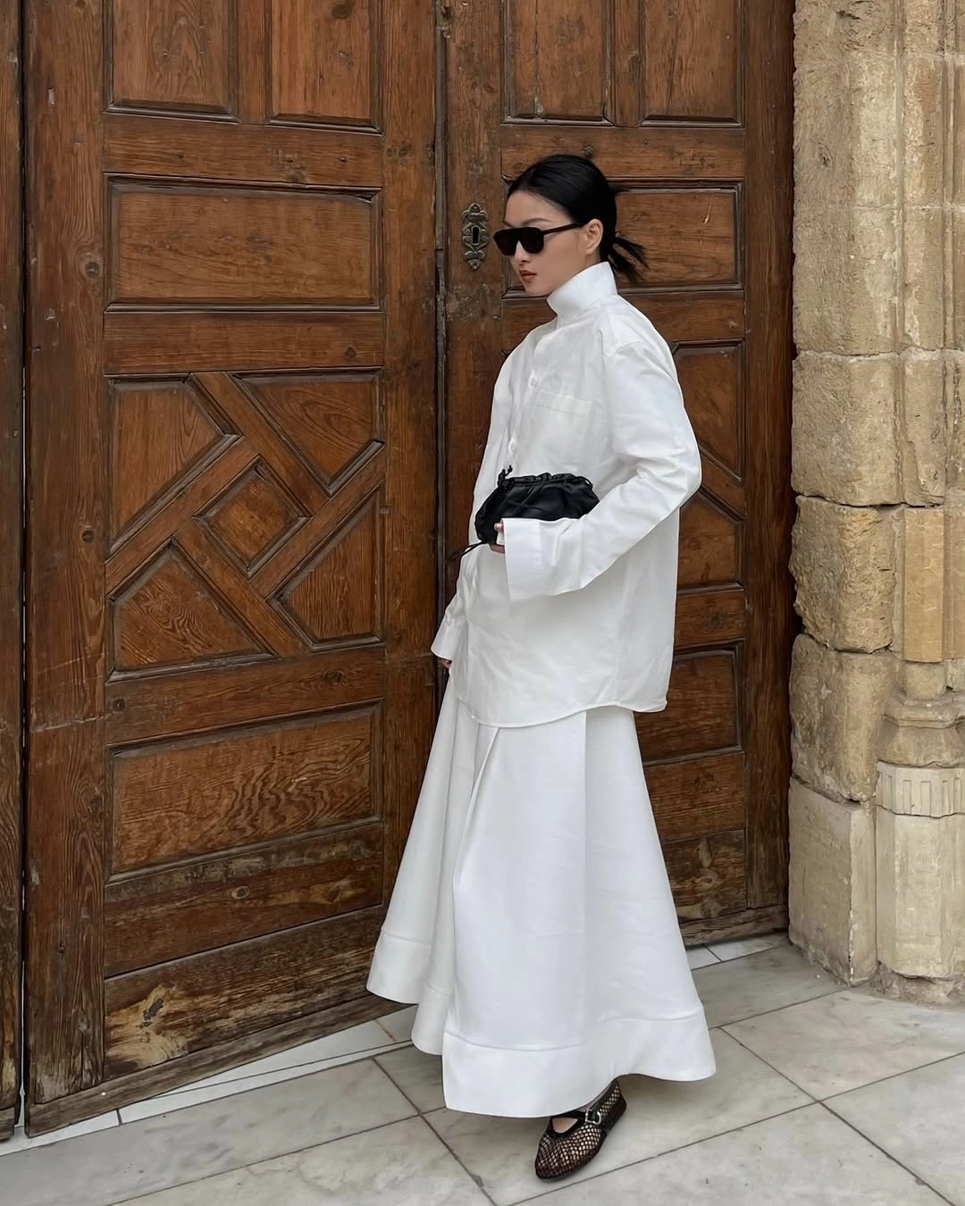 White collared shirt and long skirt with black waist accent and openwork flats