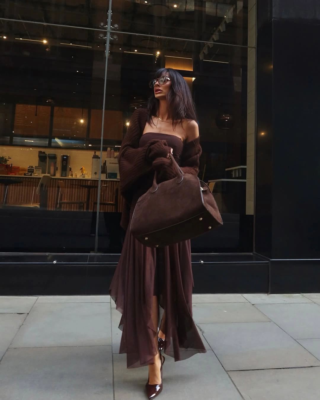 Strapless brown outfit with draped layer, large handbag, and pointed heels